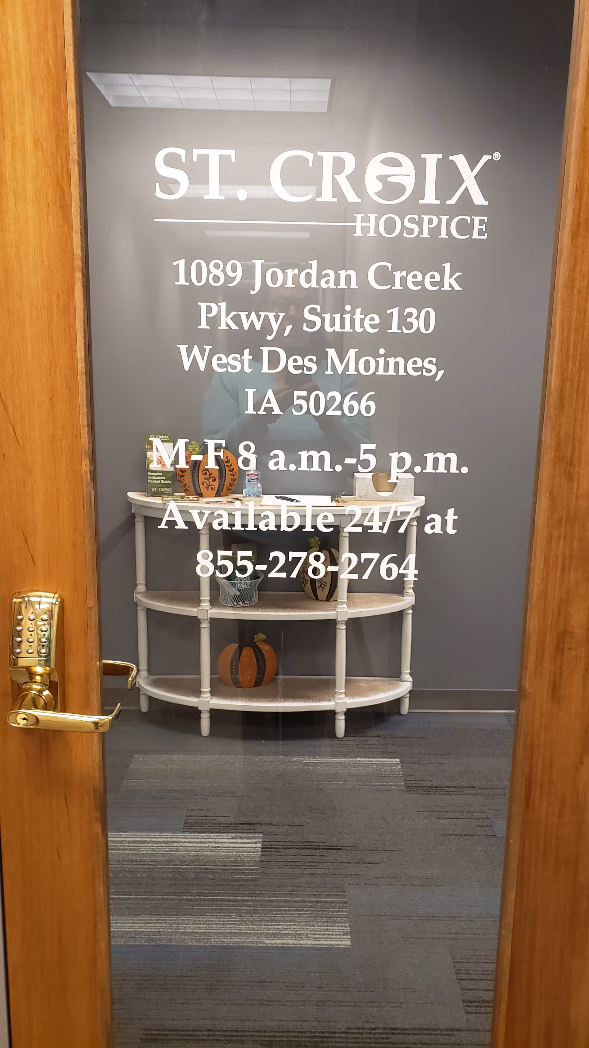 Interior glass door shows St. Croix Hospice signage, address, and a pumpkin shelf.