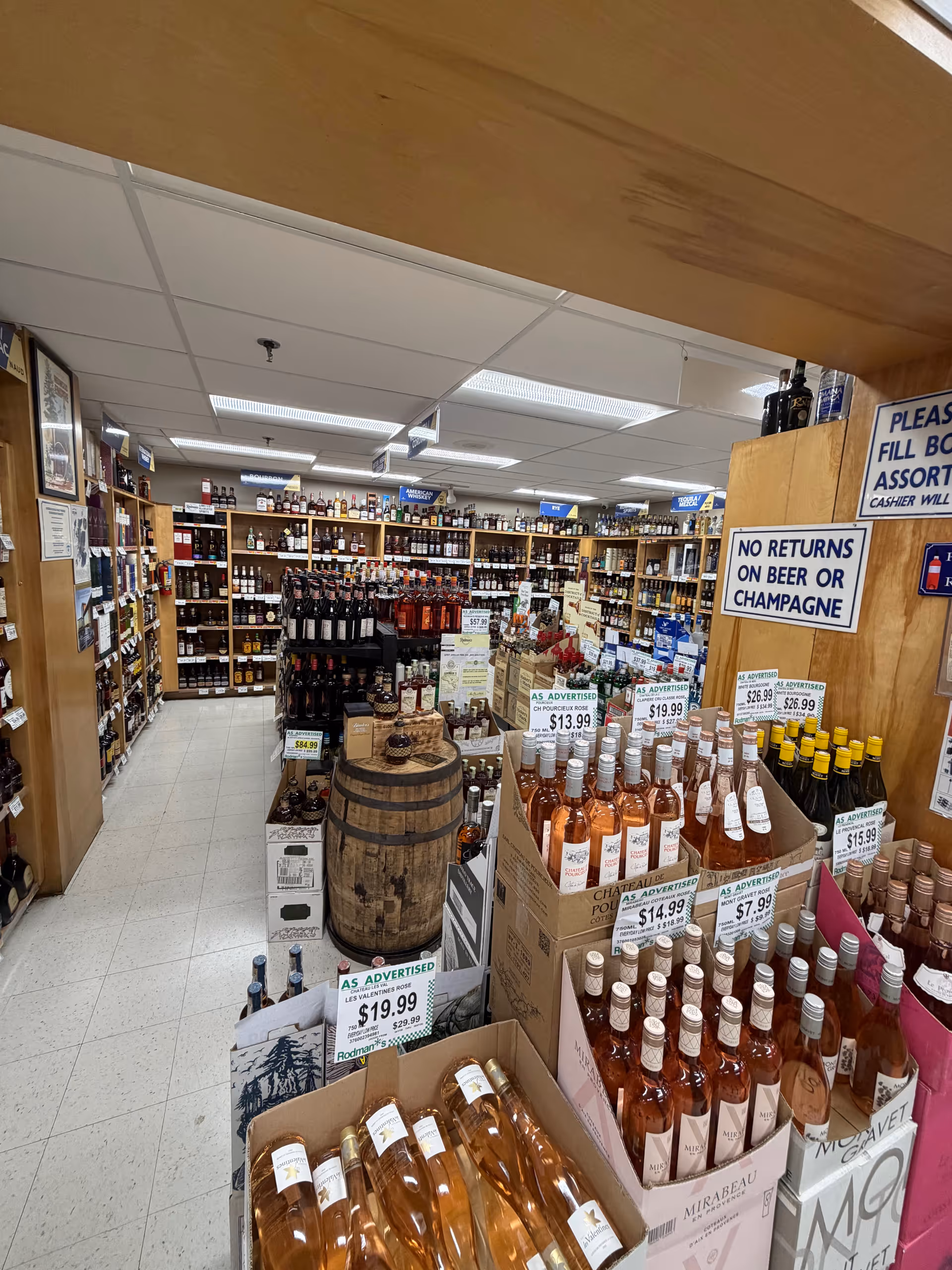 Indoor liquor store aisle in a senior living facility, shelves stocked with bottles and a barrel.