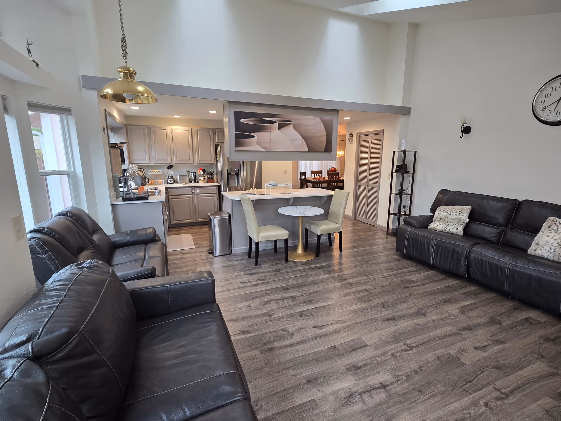 Open-concept living area with leather sofas, a kitchen island, and a dining space