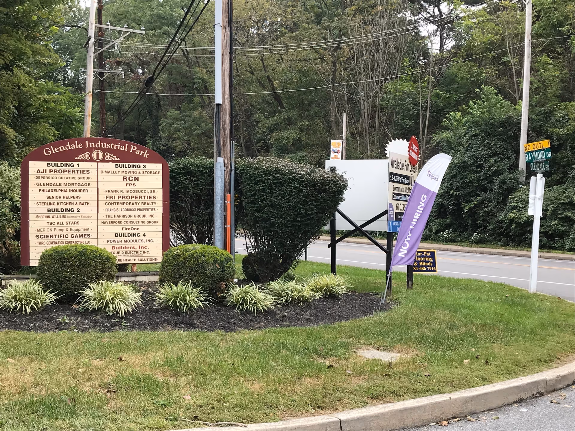 Outdoor street scene with signs and landscaping by a road and trees