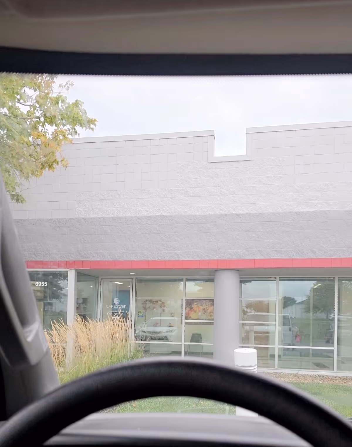 Front view of a modern facility entrance with glass doors and red accent.