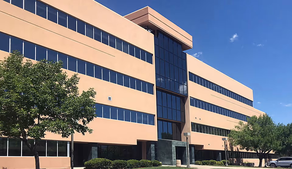 Exterior view of a Compassus facility with glass windows and trees.
