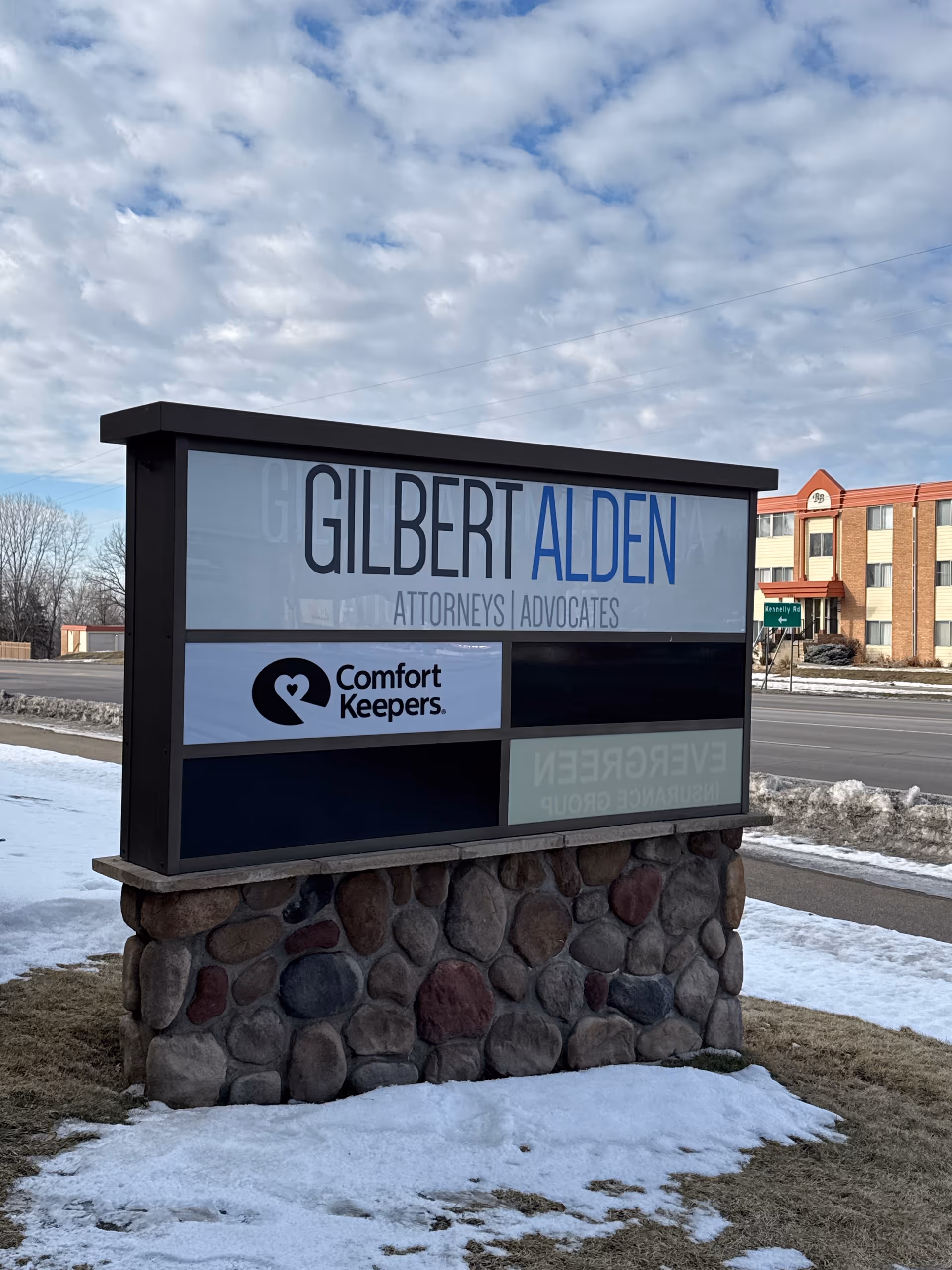 Outdoor sign for Gilbert Alden Attorneys Advocates and Comfort Keepers with a stone base.