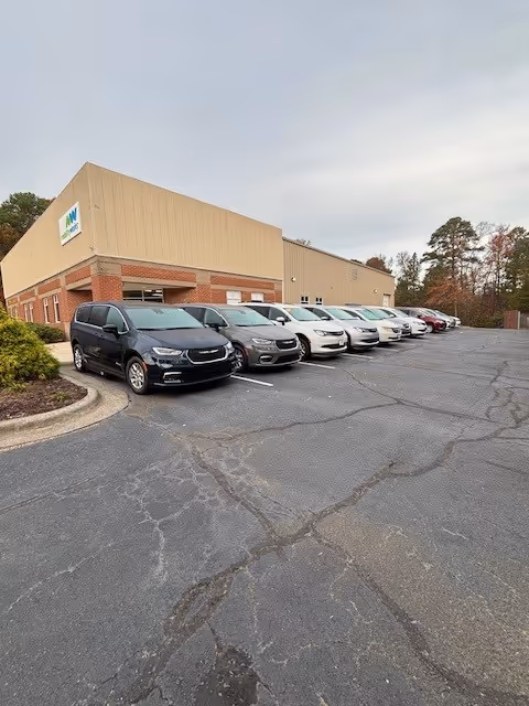 Exterior view of MobilityWorks facility with a row of parked cars in the lot