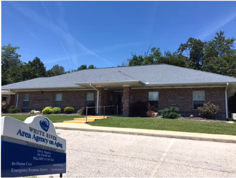 Brick single-story building with White River Area Agency on Aging sign in parking lot.