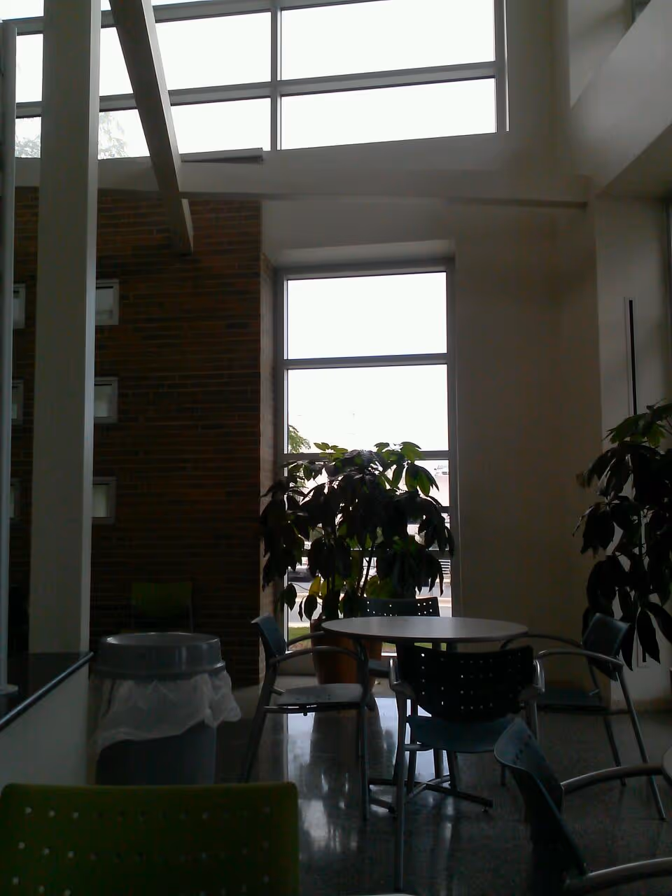 Indoor common area with a round table, chairs, and tall windows.