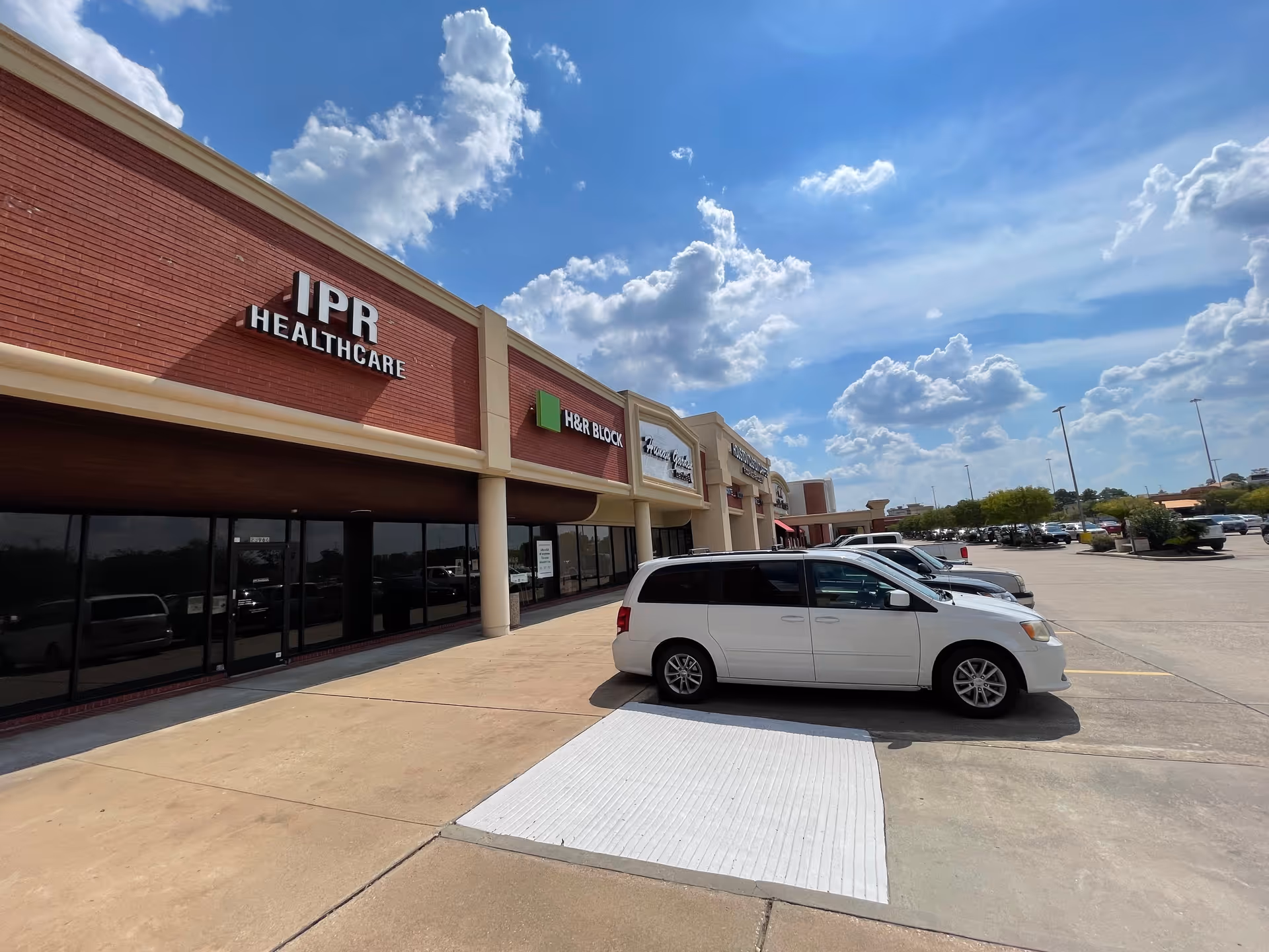 Exterior view of IPR Healthcare storefronts with a white van parked in front.