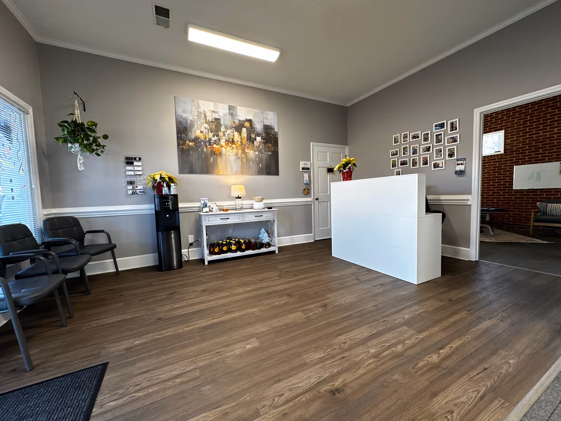 Reception area of a senior facility with a white front desk, seating, and wall art.
