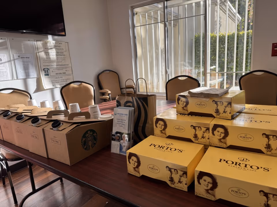 Long table with stacked boxes of meals and chairs in a bright interior room.