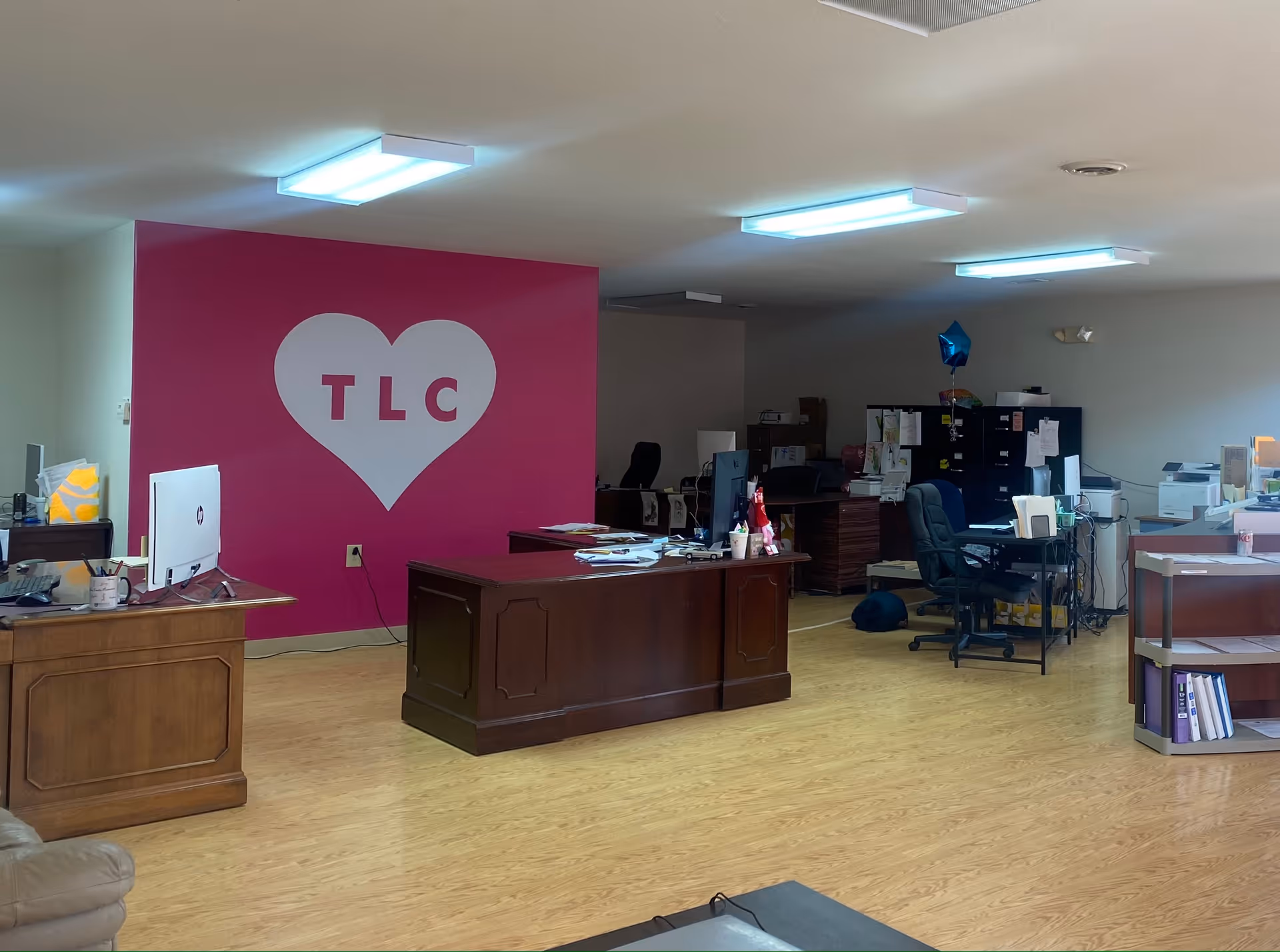 Reception area featuring a pink TLC heart wall, desks, and computer equipment.