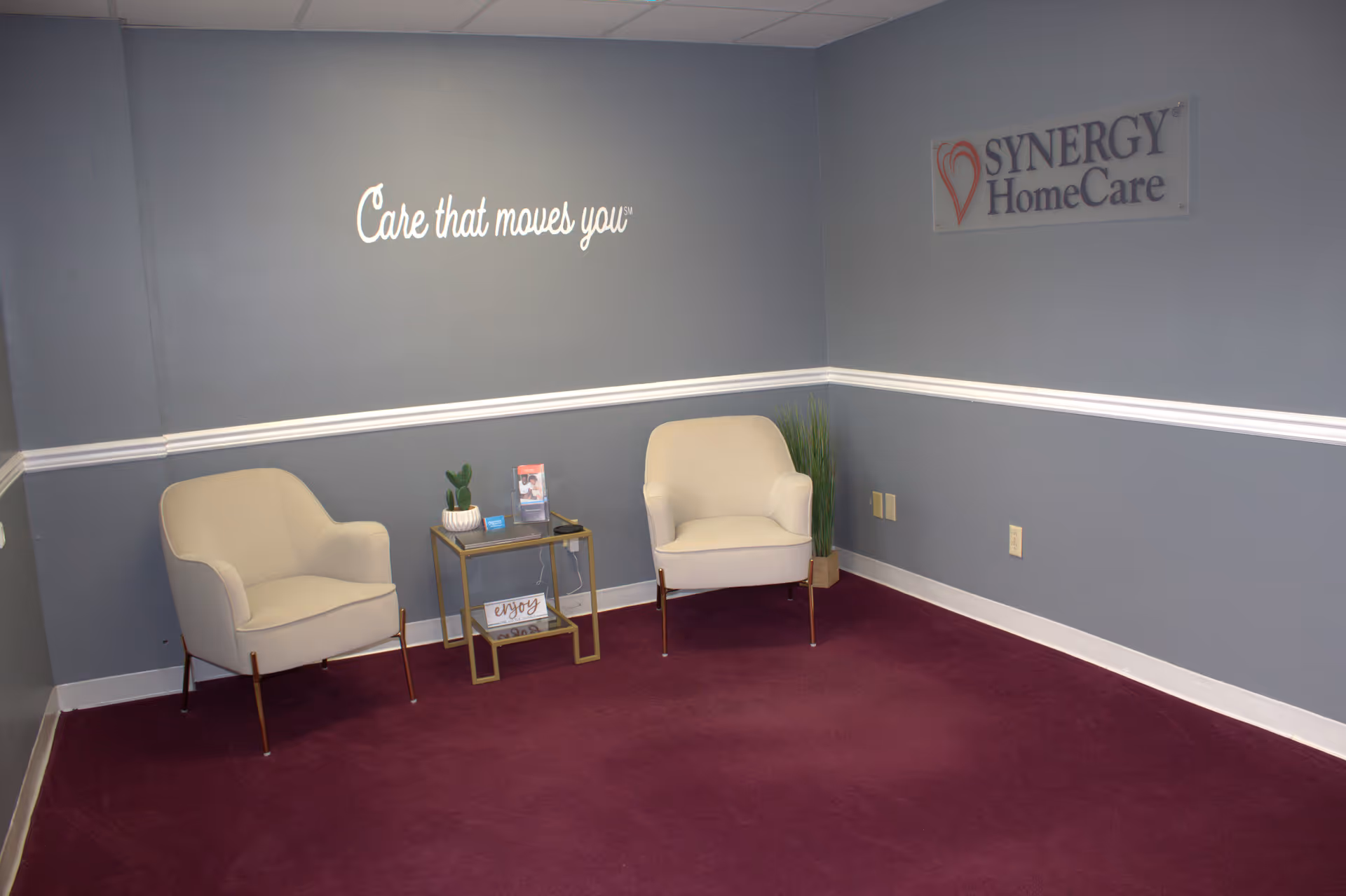 Two cream chairs flank a small table in a blue-walled waiting area