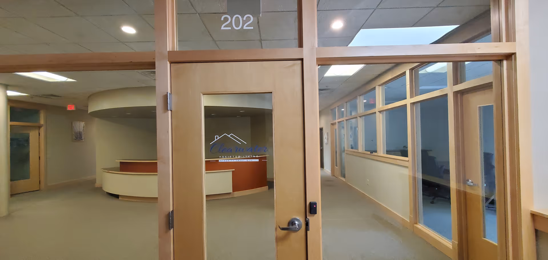 Interior hallway of Clearwater Assisted Living with a reception desk visible through glass doors.