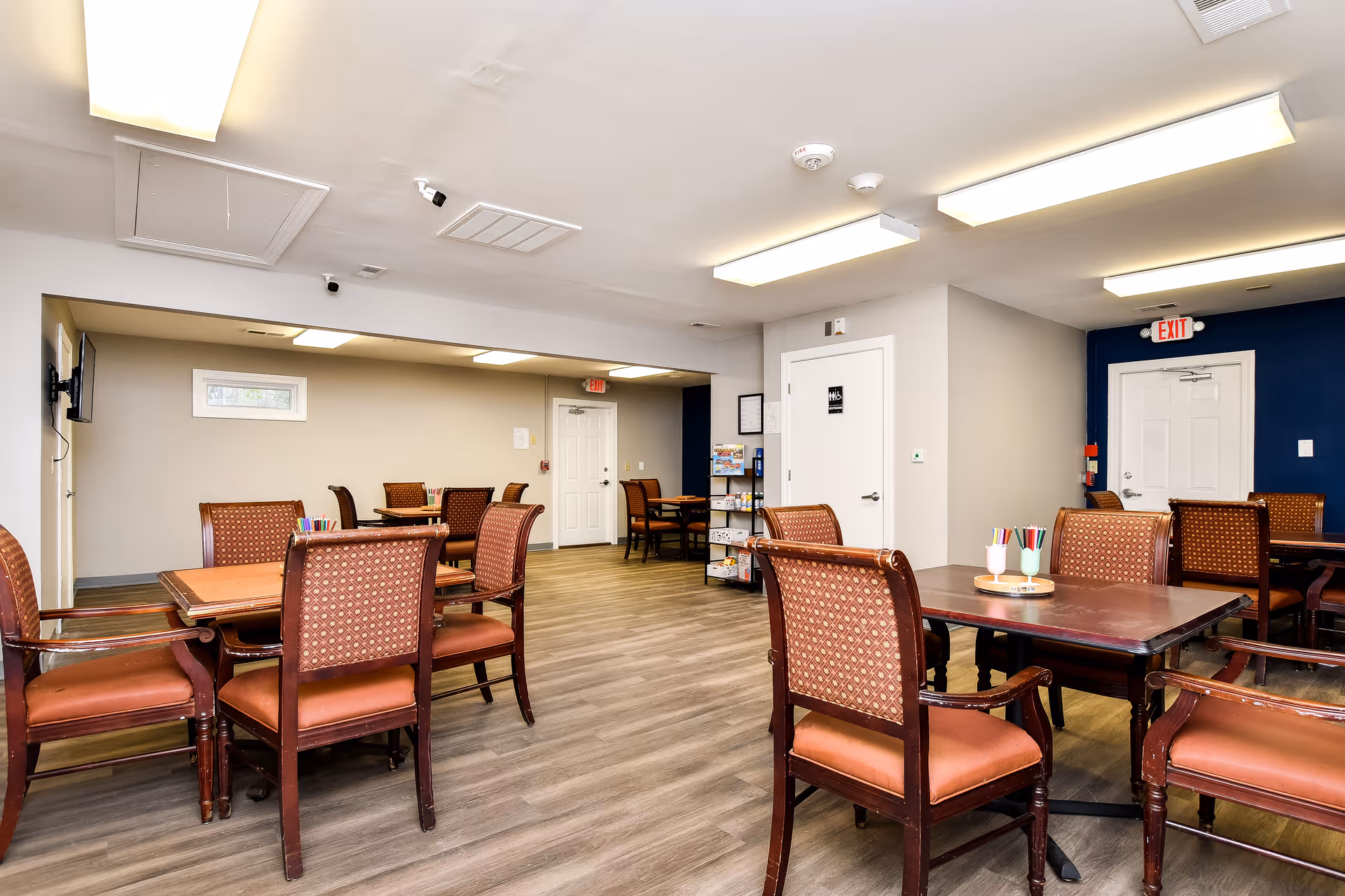 Bright dining room in Elite Home Care and Day Centers with several tables and upholstered chairs.