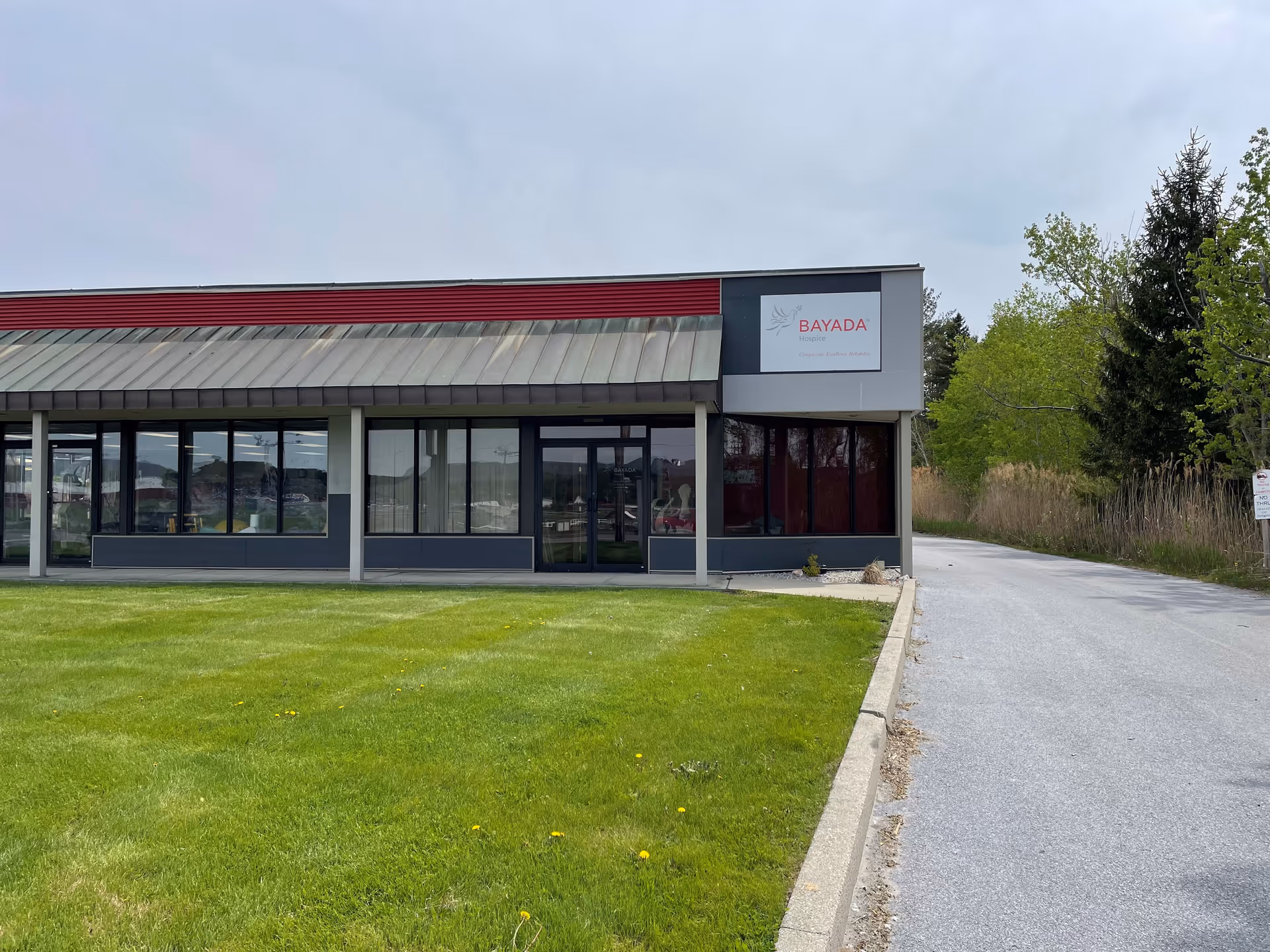 Modern Bayada Hospice exterior with glass storefront, manicured lawn, and driveway.