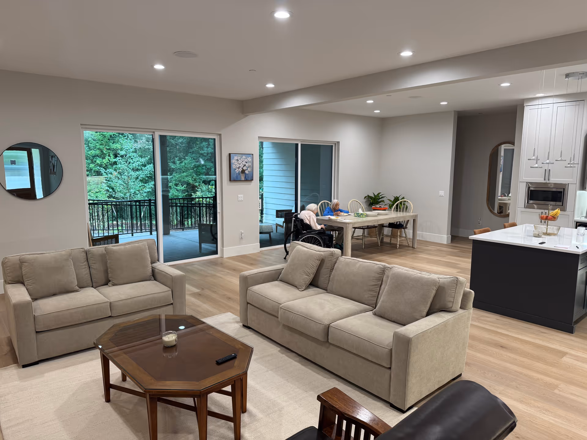 Open-concept living area in a senior home with beige sofas and a dining table.