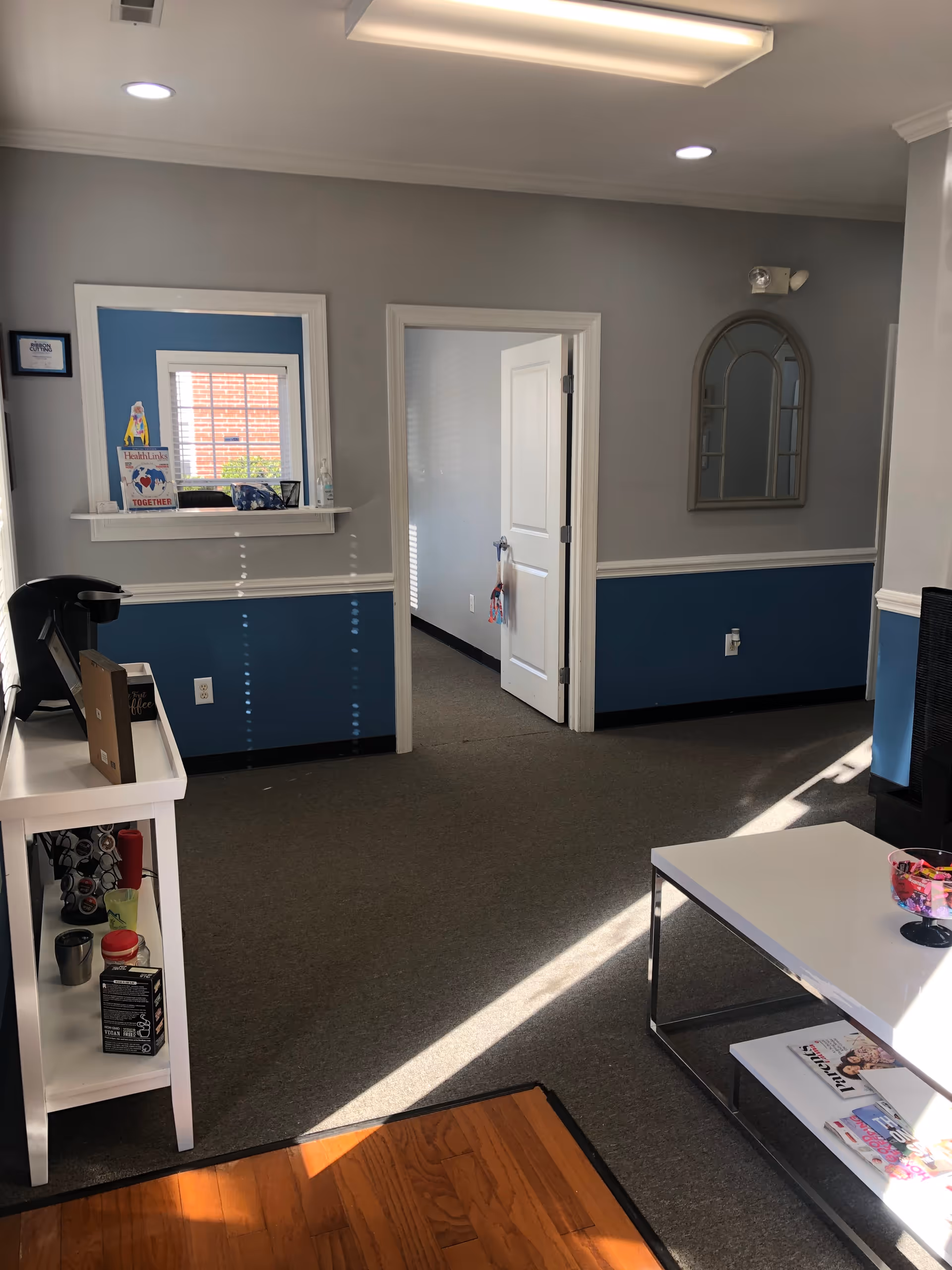 Interior lobby with blue wainscoting, doorway, window, and magazine table.