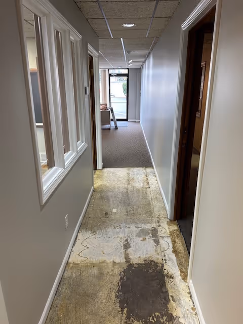 Narrow hallway in a senior home with doors, windows, and a lounge at end.