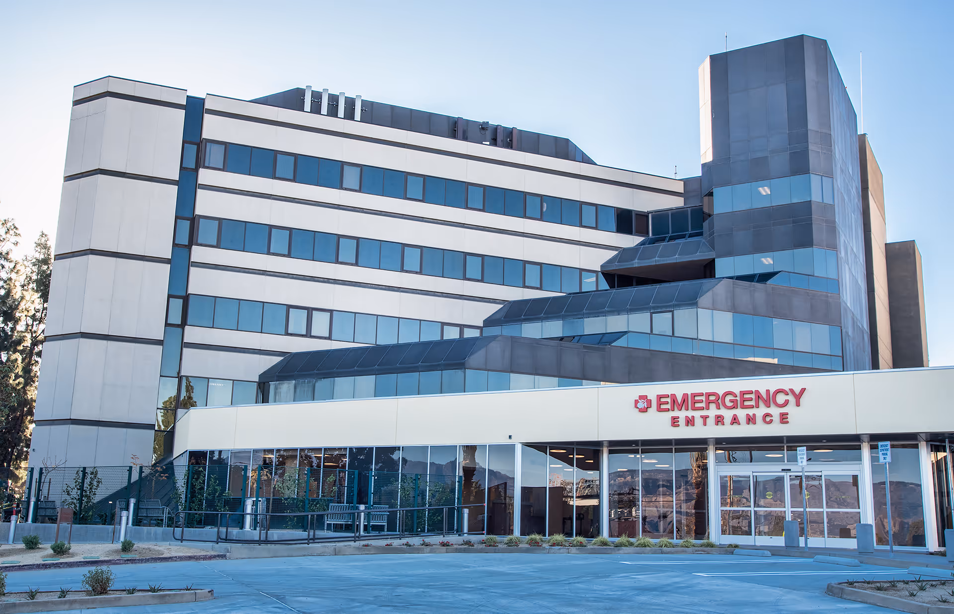 Modern multistory hospital exterior with emergency entrance and glass doors.