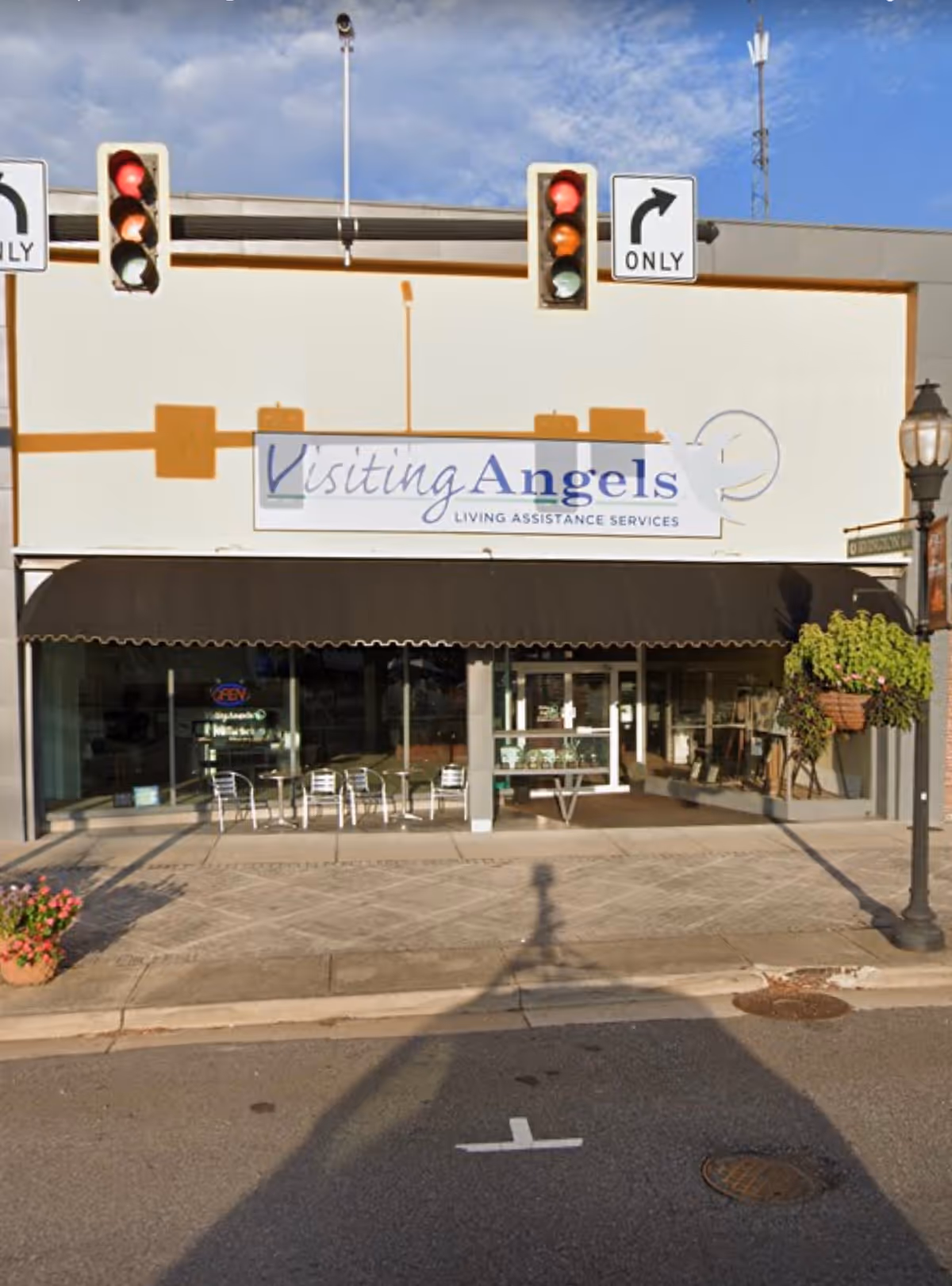 Exterior view of Visiting Angels Senior Home Care storefront with sign, awning, outdoor seating.