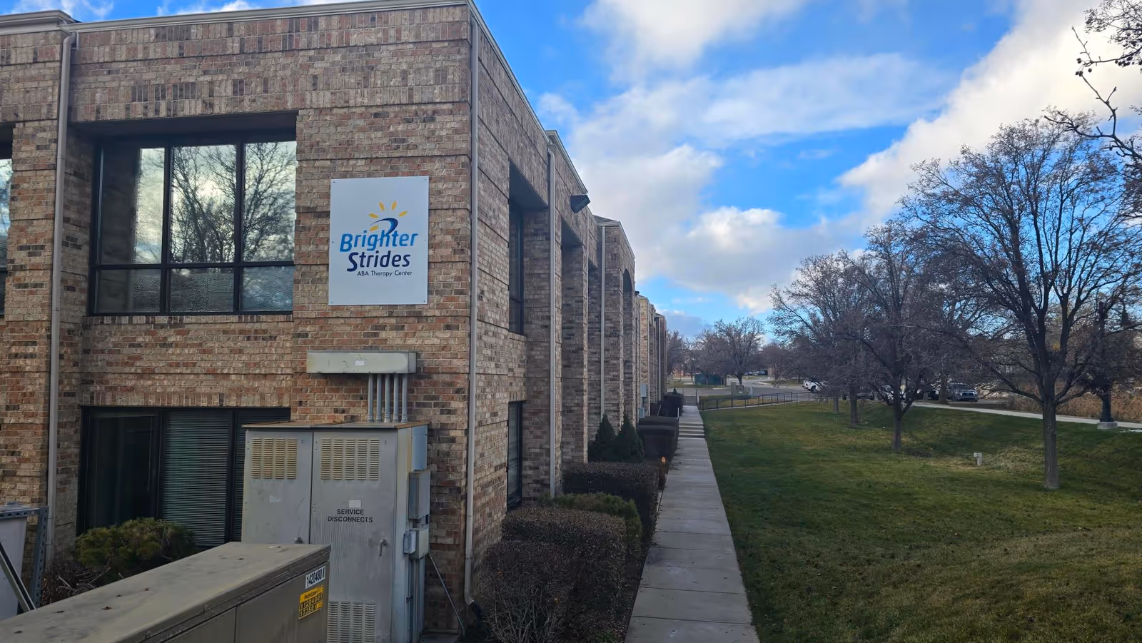 Exterior brick building with Brighter Strides ABA Therapy sign along sidewalk.