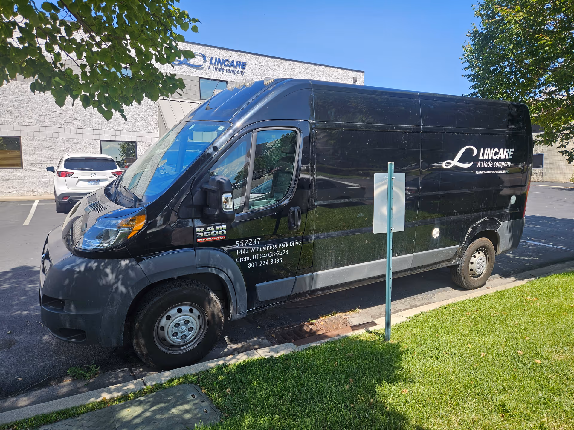 A black LINCARE van parked in front of a senior living facility building.