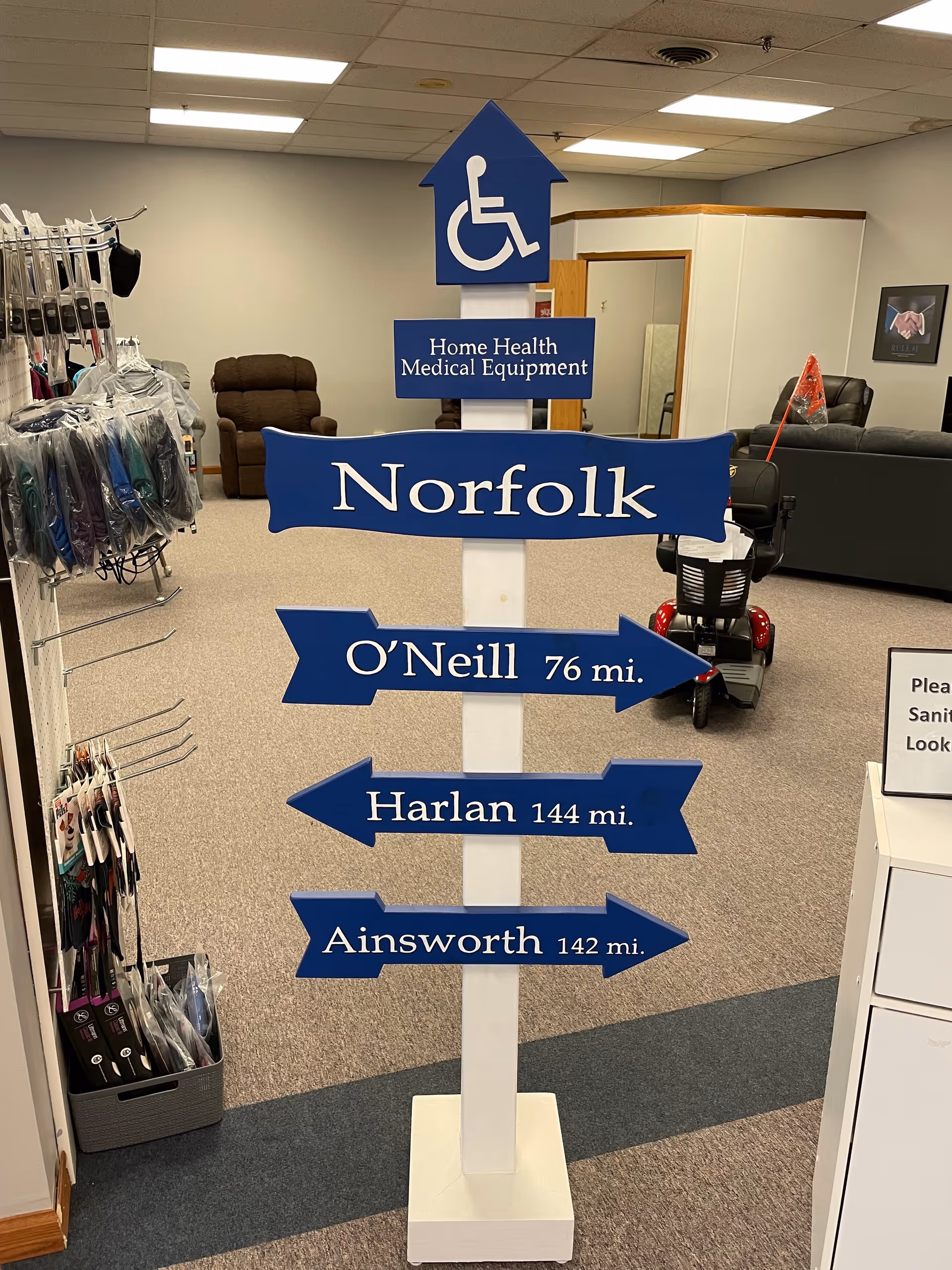 Indoor medical equipment showroom with a tall blue directional sign and wheelchair icon