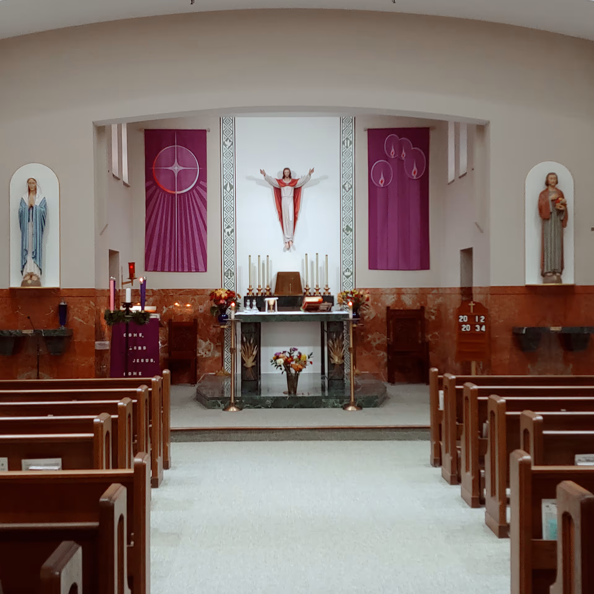 Interior of a chapel with altar, statues, candles, and wooden pews.