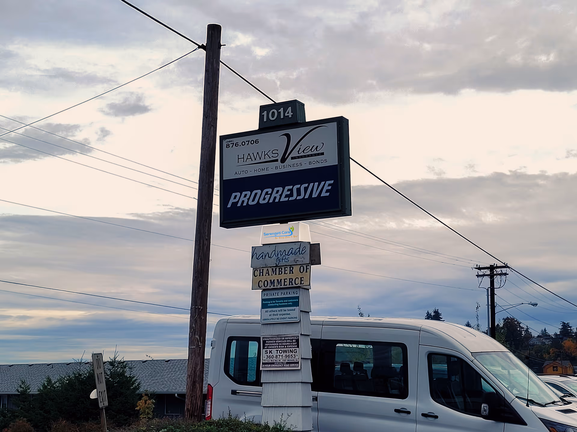 Exterior street scene with a white van and multiple signs near a pole