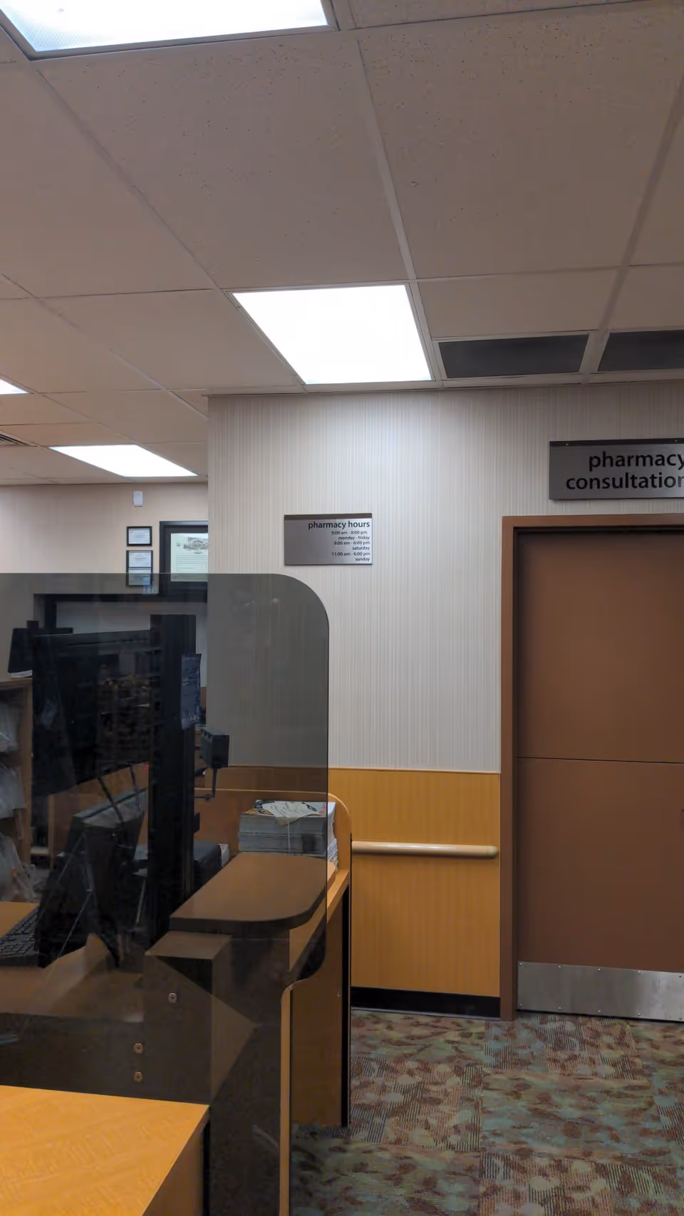 Pharmacy area inside a senior facility with computer station and curved glass partition.