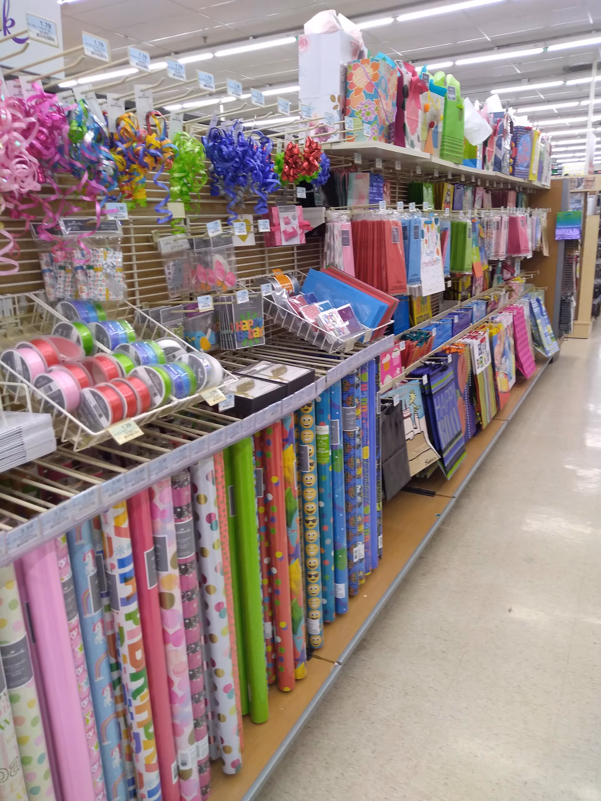 An interior store aisle filled with colorful gift wrap and party supplies on shelves.
