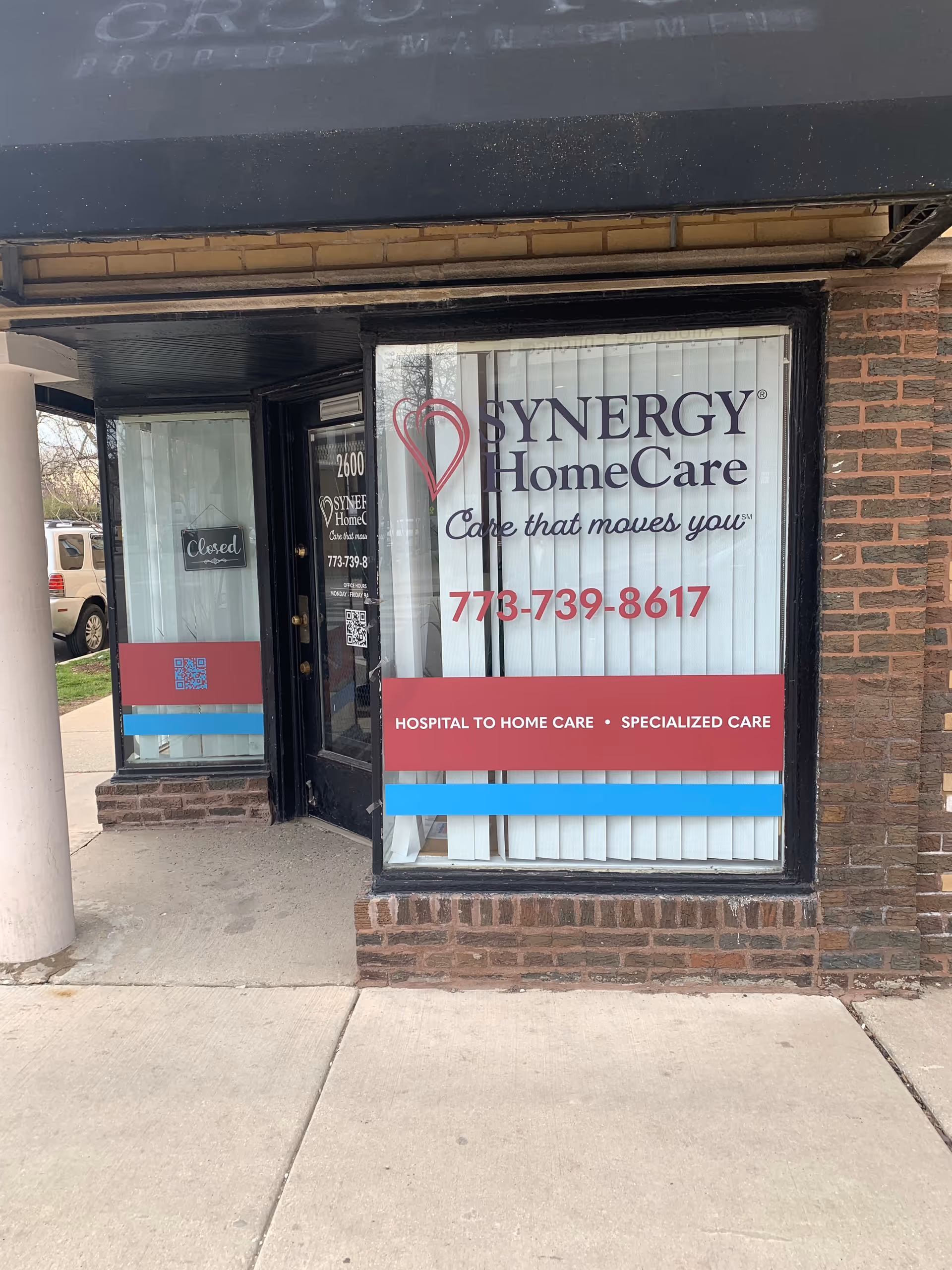 Exterior view of SYNERGY HomeCare storefront with brick facade and large window sign.