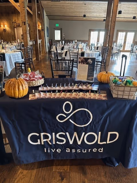 Promotional display table with Griswold banner, pumpkins, and snacks in a dining hall.