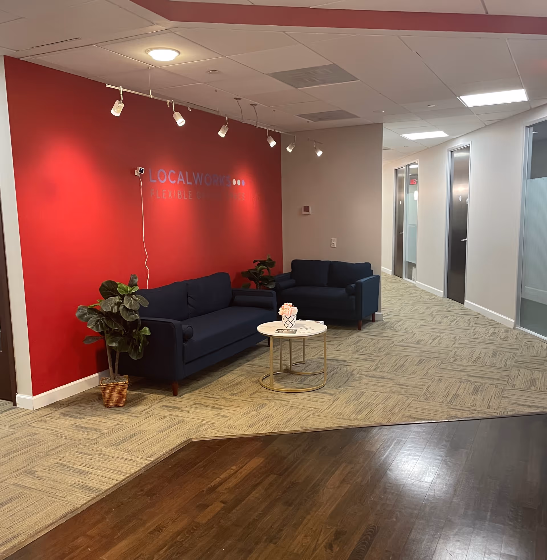 Bright, modern lounge with a red accent wall, blue couches, and a round coffee table.