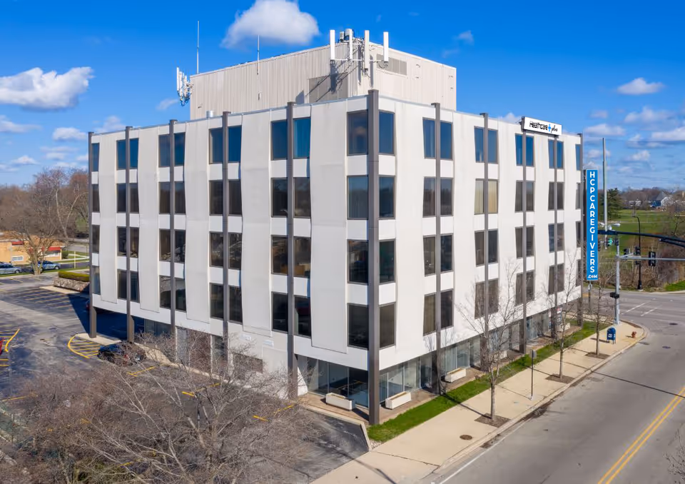 Exterior of a modern, multi-story senior living facility with large windows and a vertical HPC sign.