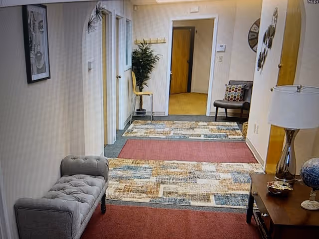 Interior hallway of Comfort Keepers Home Care with bench seating, plants, and doorway to rooms.