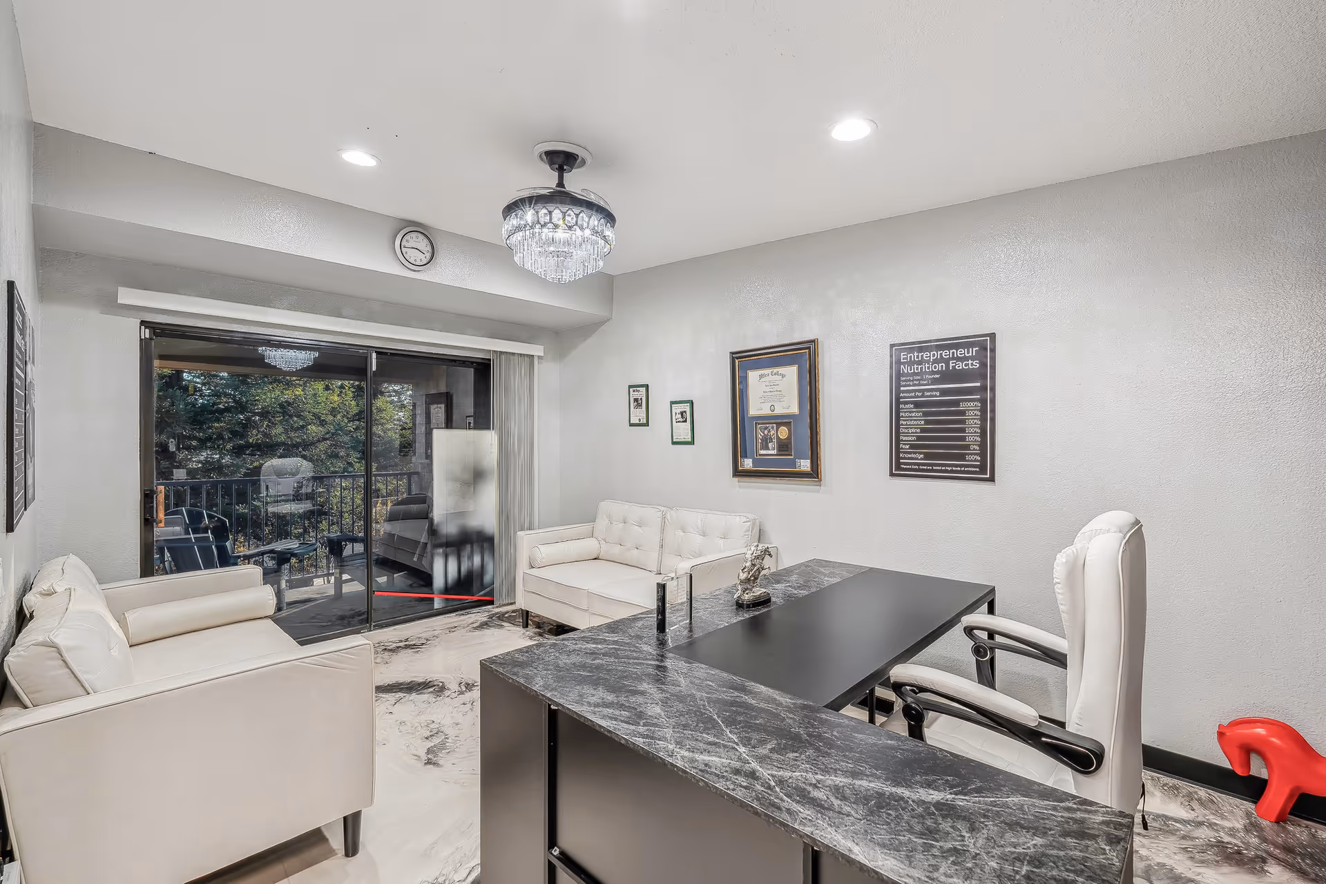 Modern reception area with a marble desk, white seating, framed certificates, and sliding glass doors.