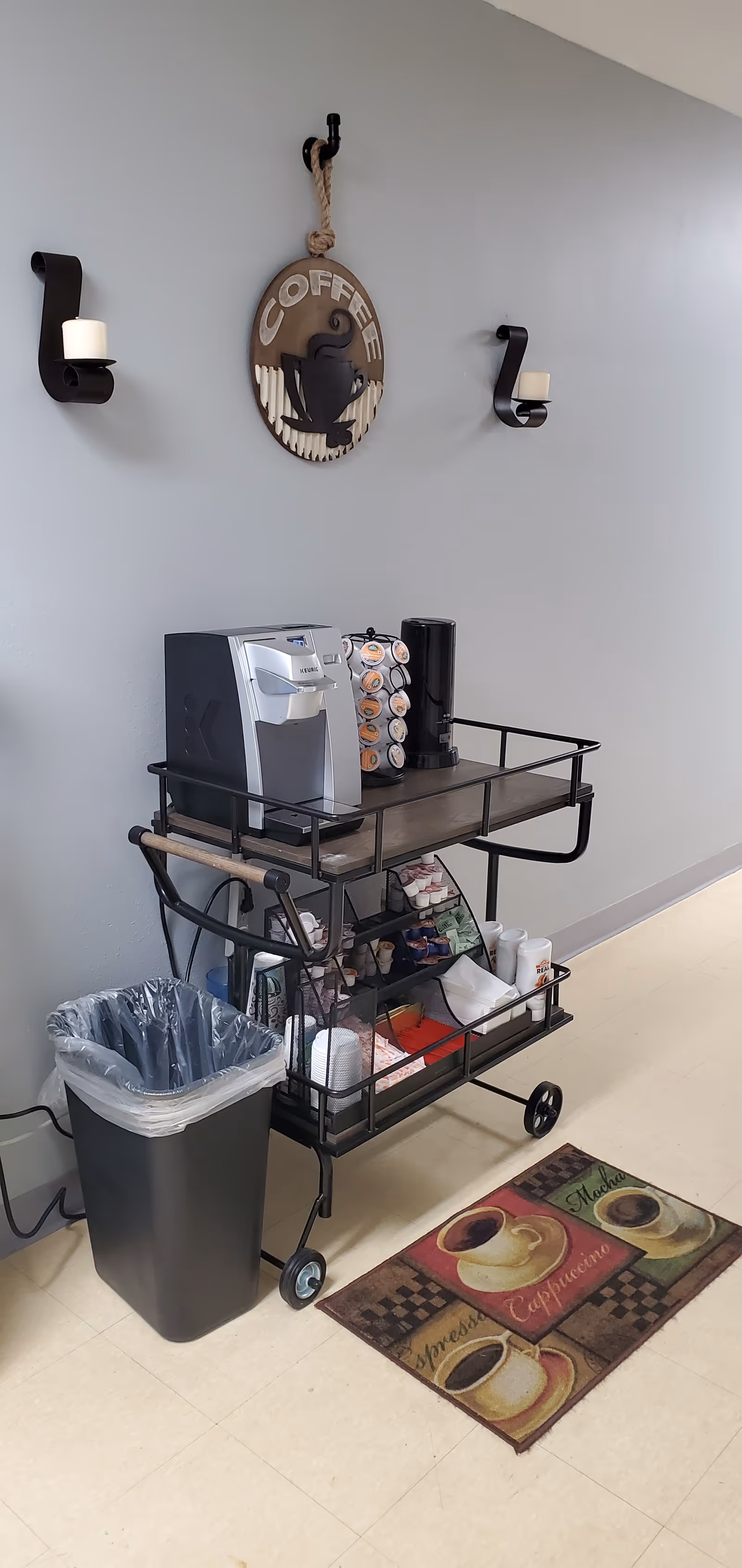 Coffee station on a wheeled cart with a Keurig, cups, and supplies.