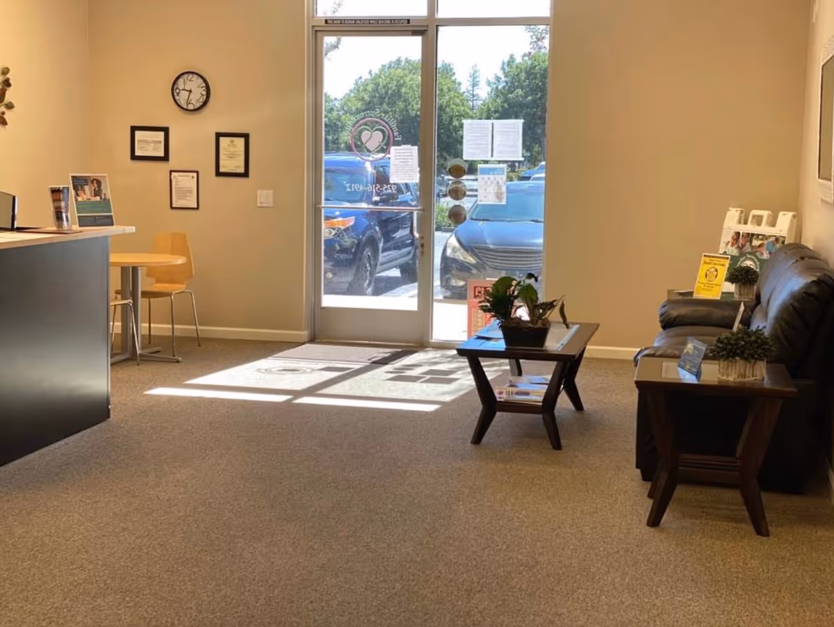 Sunlit lobby of Familiar Surroundings Home Care with a reception desk, seating area, and glass door.