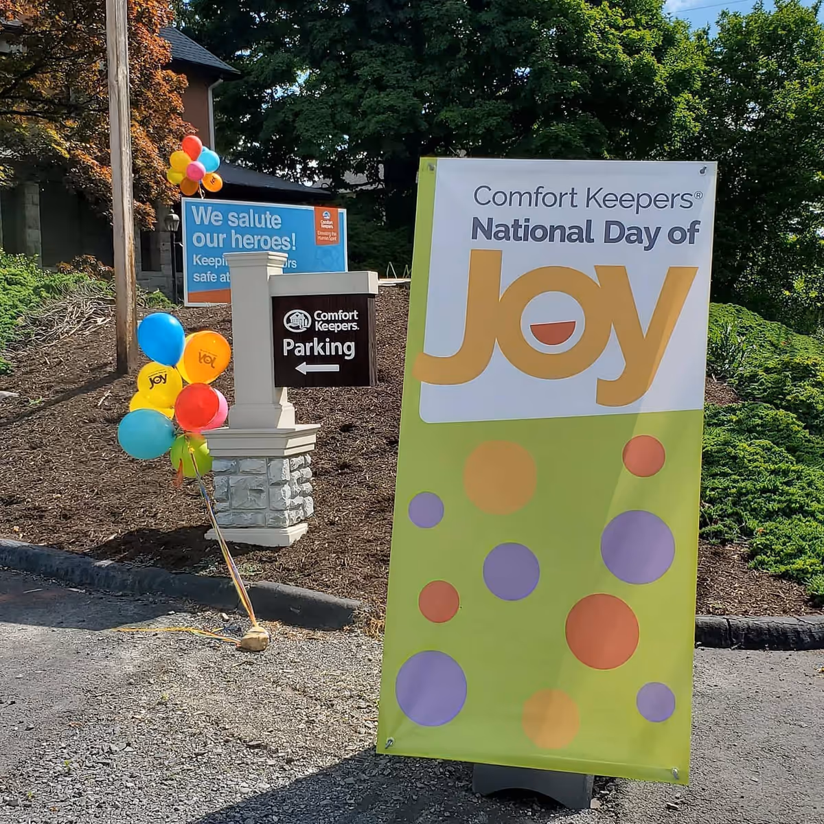Outdoor banner for Comfort Keepers National Day of Joy with balloons and signs