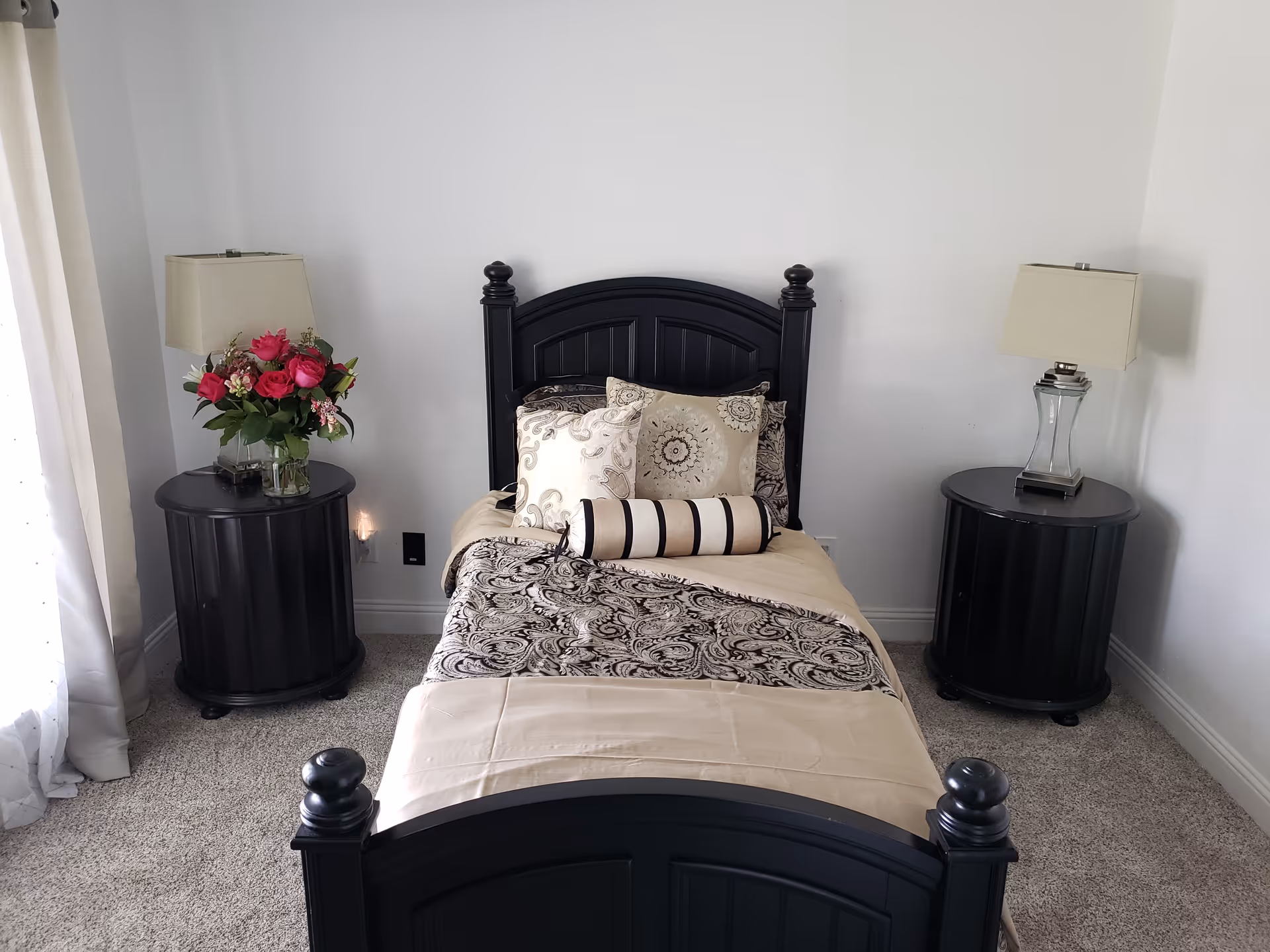 Dark wood bed with matching nightstands, lamps, and a floral centerpiece in a tidy bedroom.