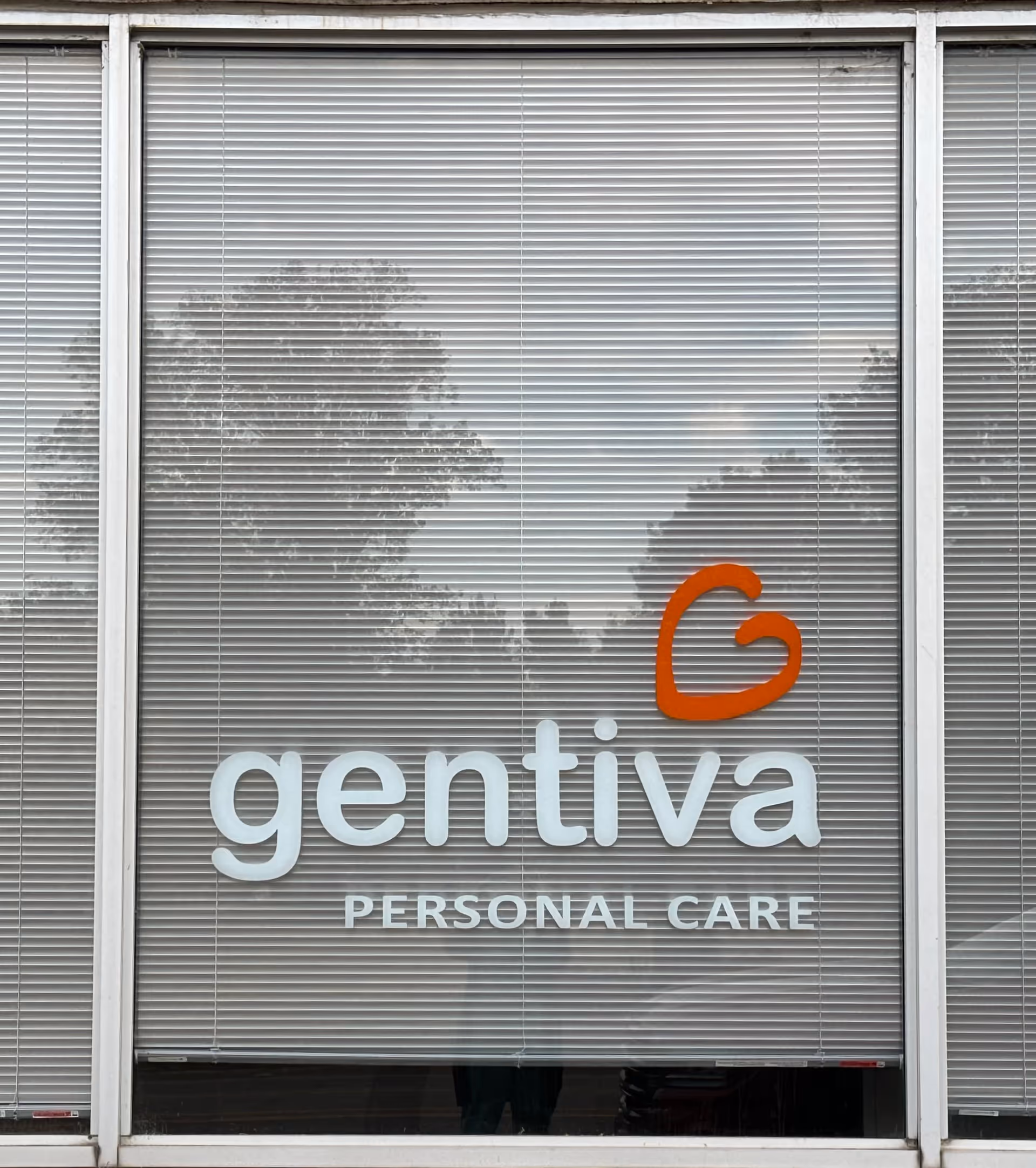 Window storefront displaying Gentiva Personal Care logo with blinds on the building front.