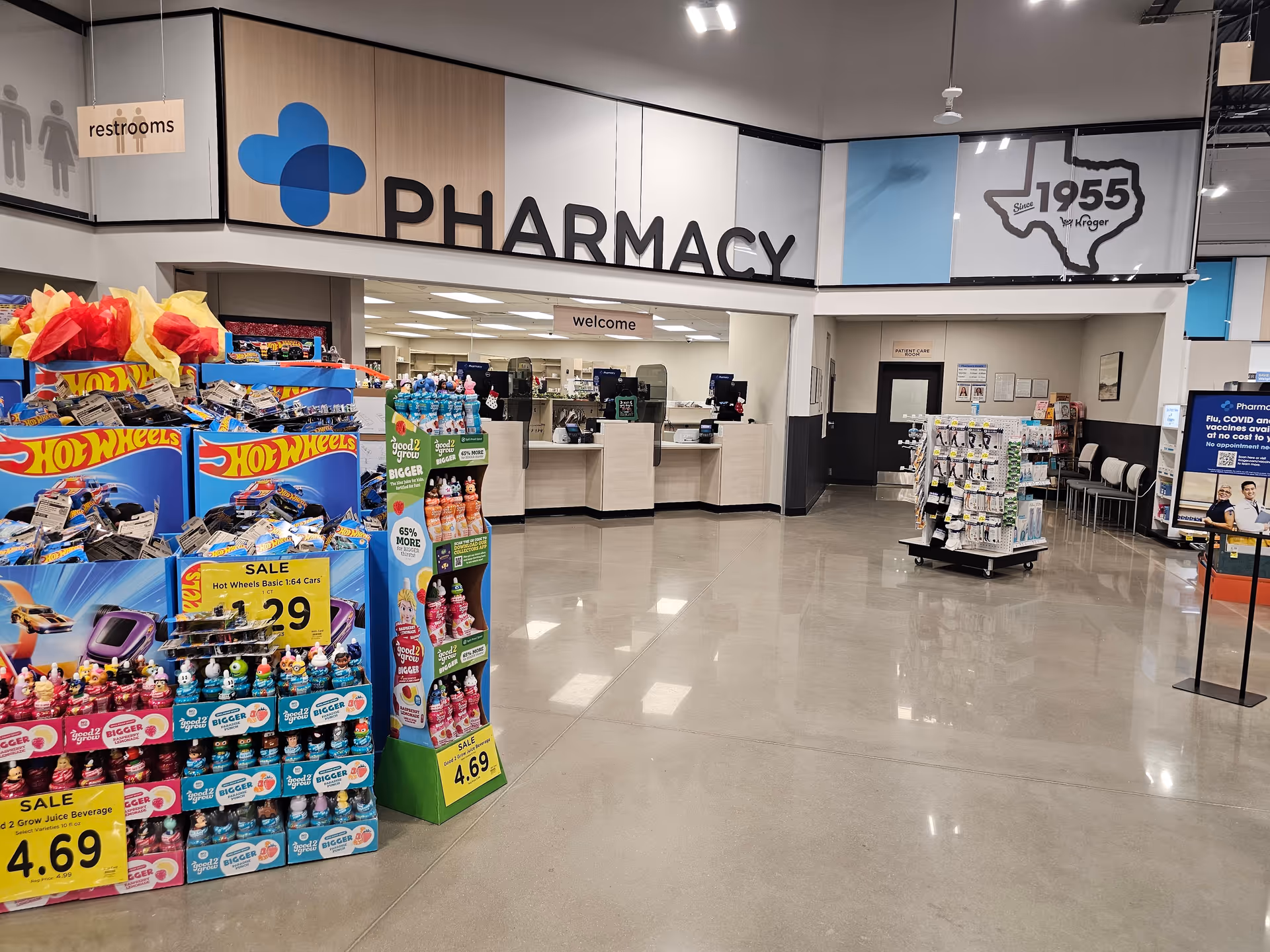 Interior of a Kroger Pharmacy area with checkout counters, signs, and product displays.