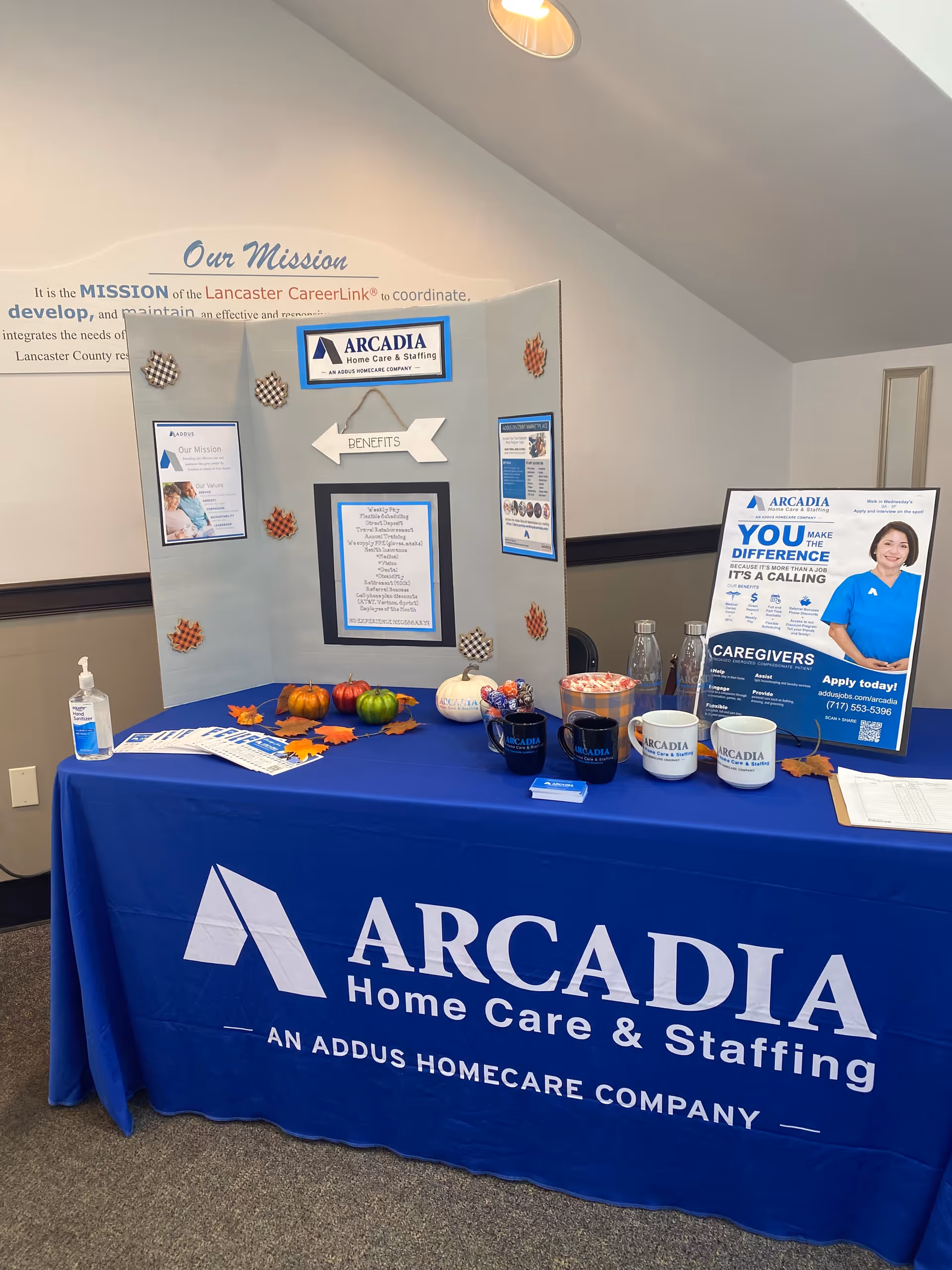 Blue Arcadia display table with brochures inside a facility lobby.