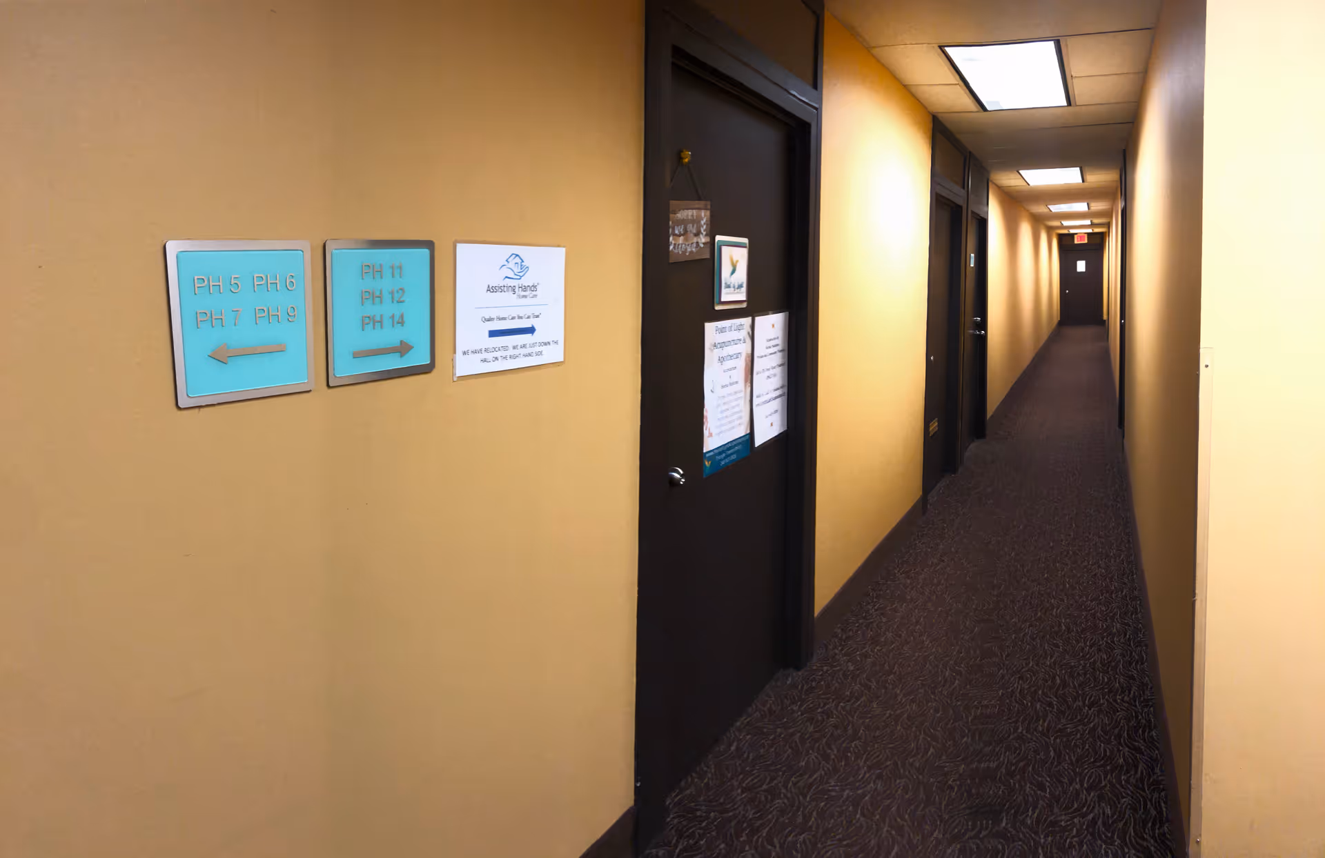 Long beige hallway with closed doors and wall signs in a care facility