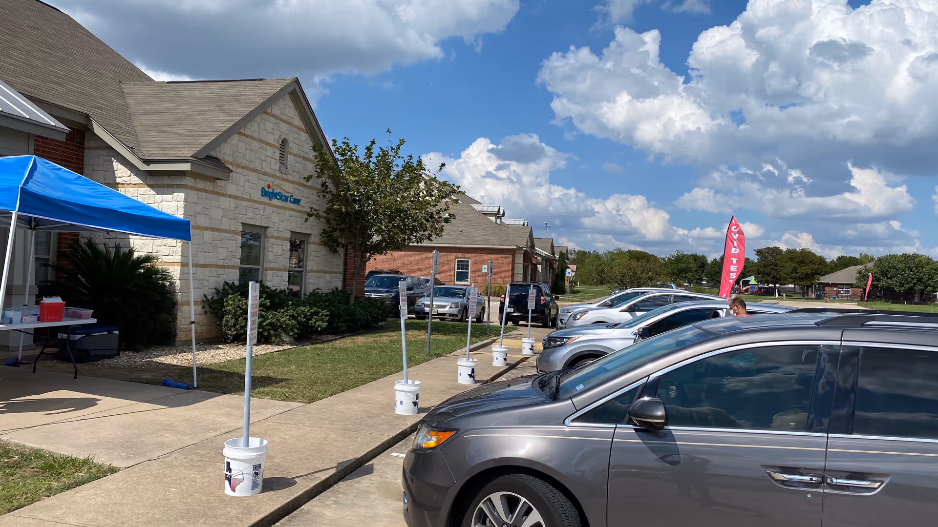Exterior view of BrightStar Care building with cars parked and a blue canopy tent outside.