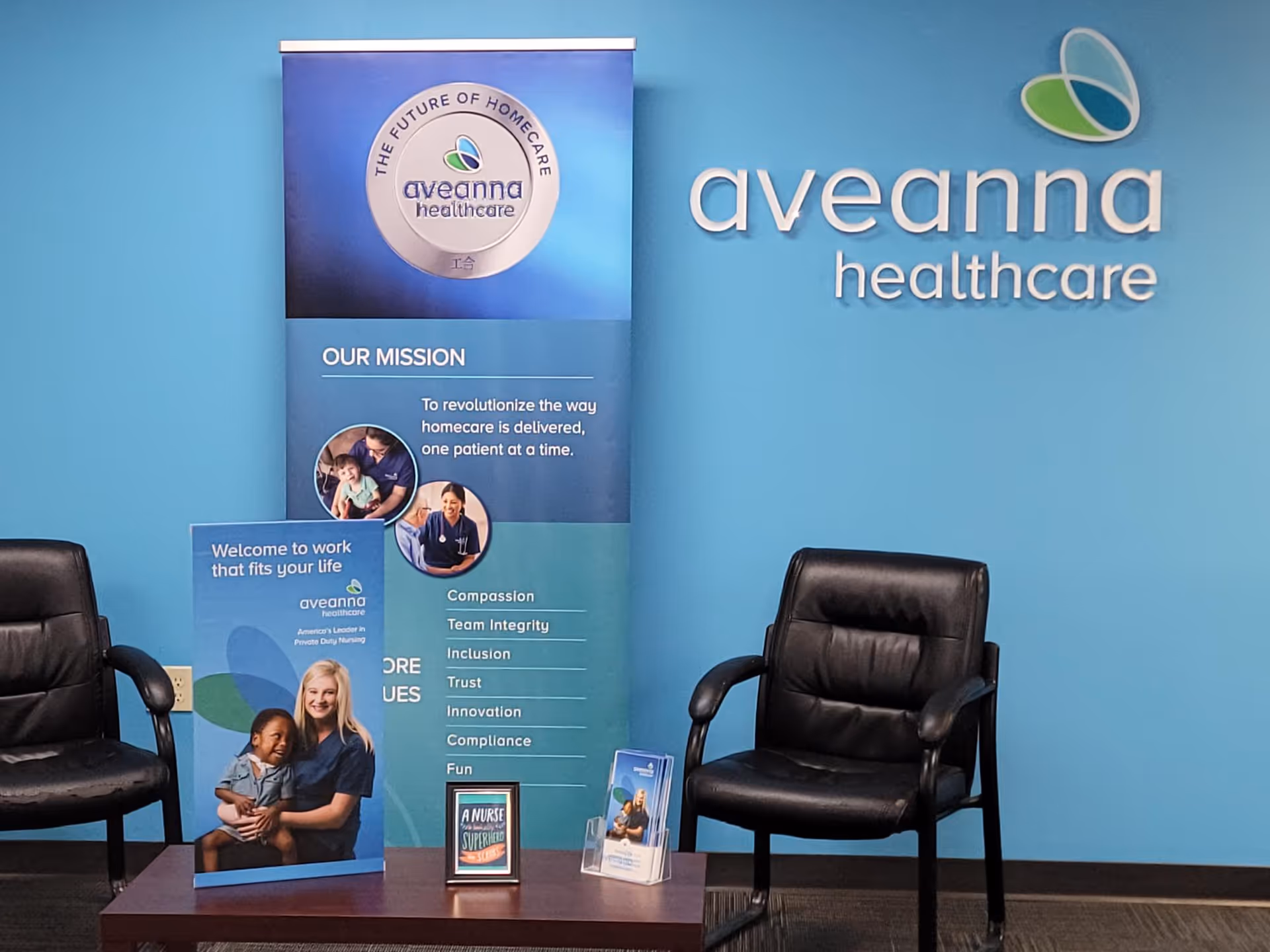 Blue lobby interior with Aveanna Healthcare signage, two black chairs, and a promotional banner.