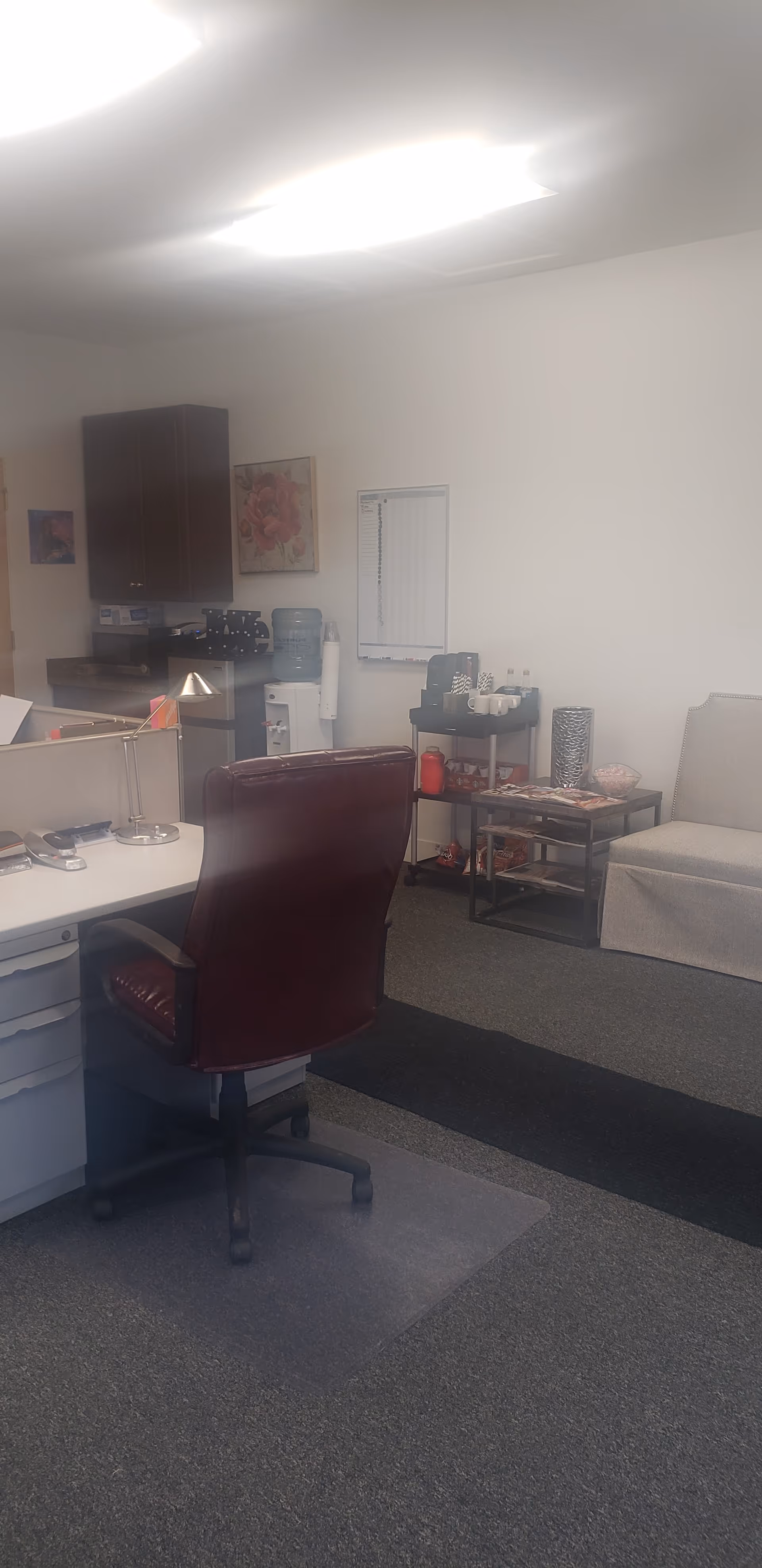 Office and waiting area in a senior care facility with desk, chairs, and coffee station.