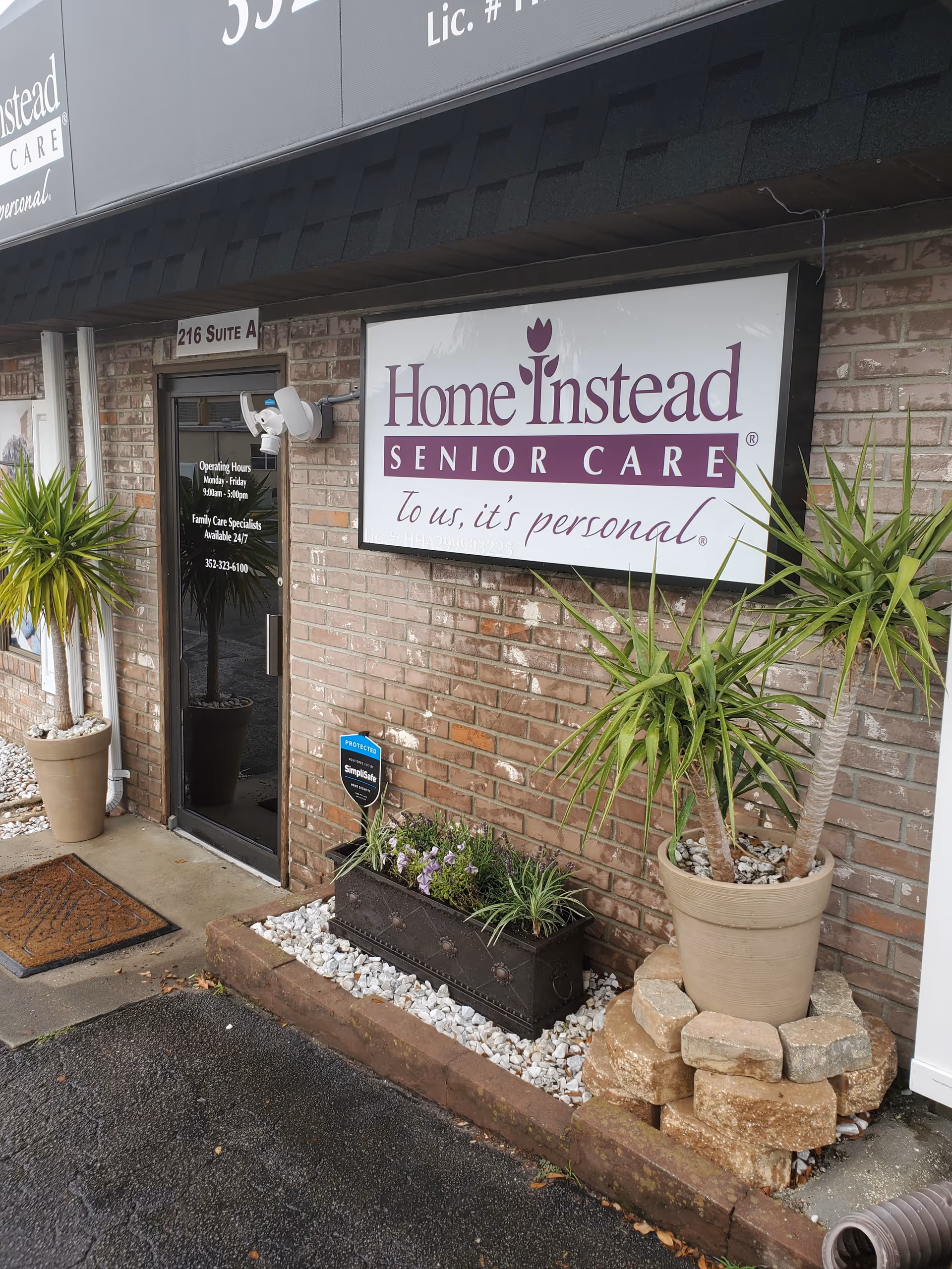 Exterior view of Home Instead Senior Care storefront with brick wall and plants