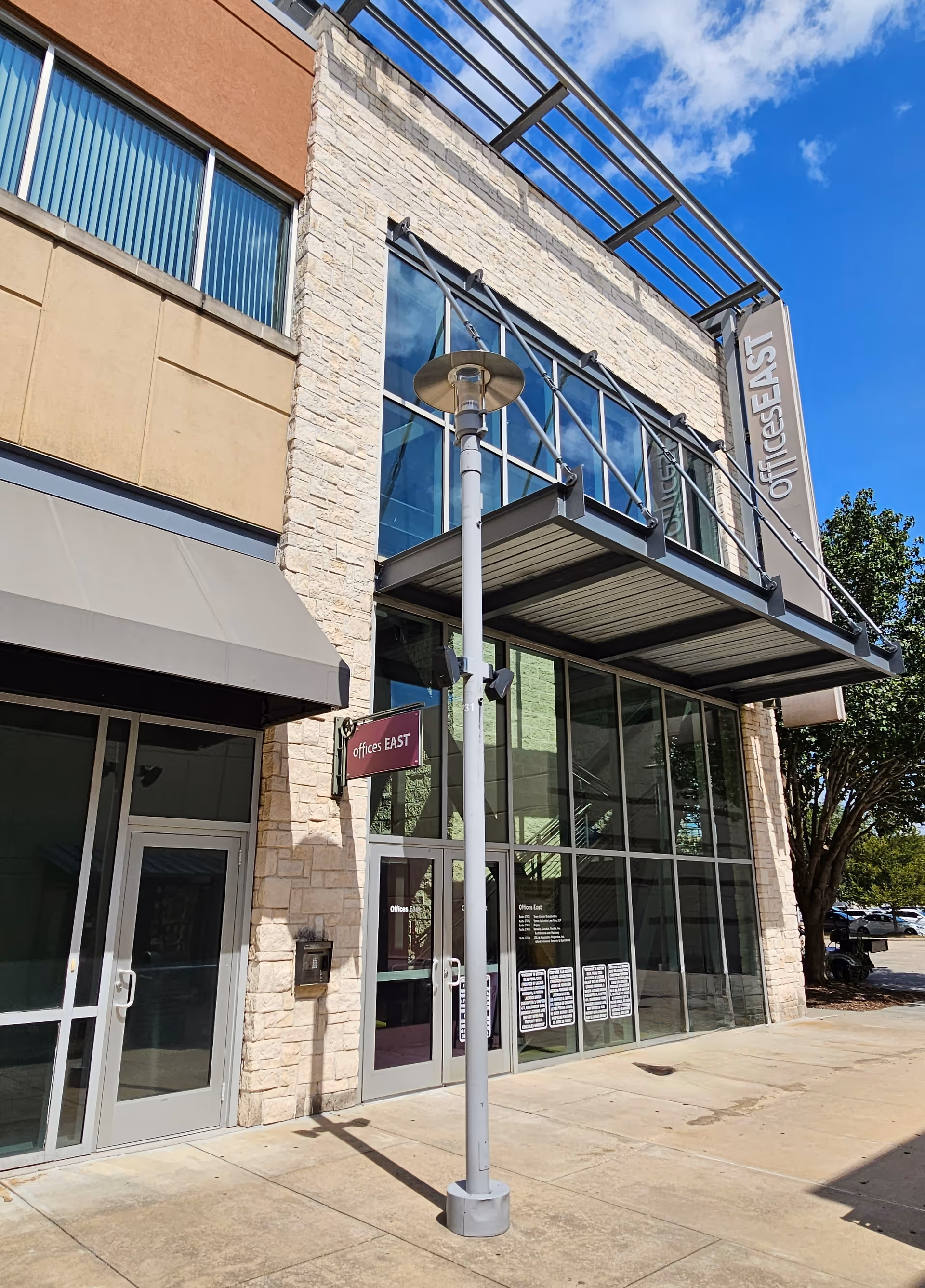 Modern office building front with glass windows and a street sign