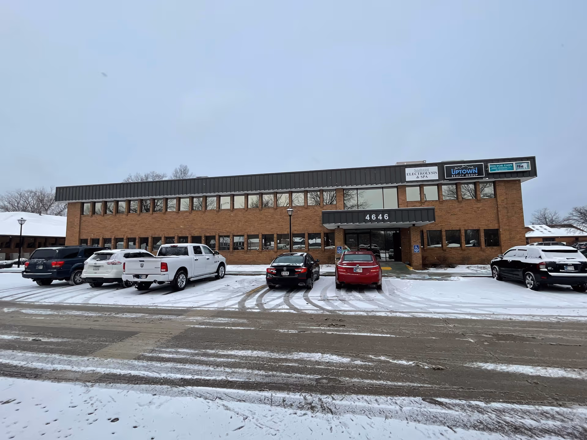Brick two-story building with a front entrance canopy and snow-covered parking lot.
